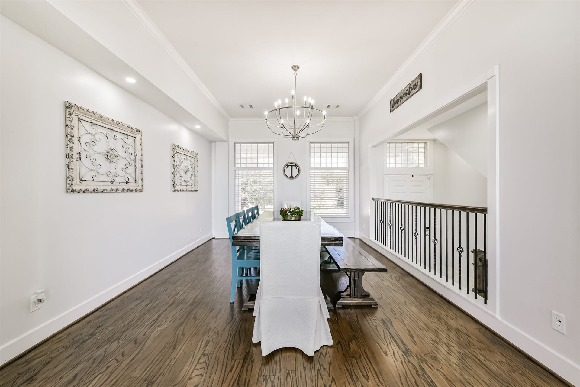 Dining area featuring hardwood floors, a stylish chandelier, and ample natural light from large windows, perfect for hosting gatherings.