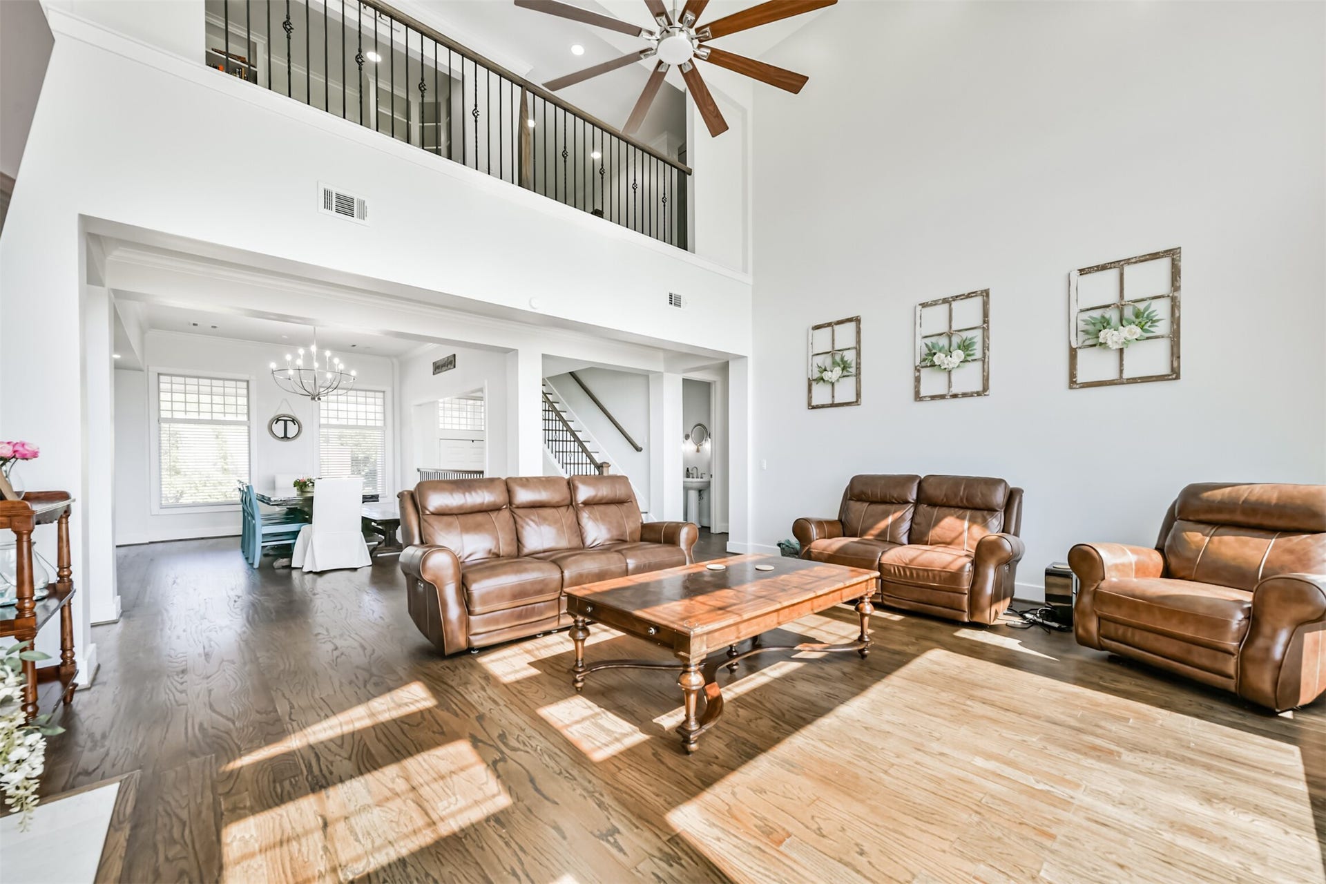 Spacious living area with high ceilings, large windows, and elegant hardwood floors, seamlessly flowing into a bright dining space.
