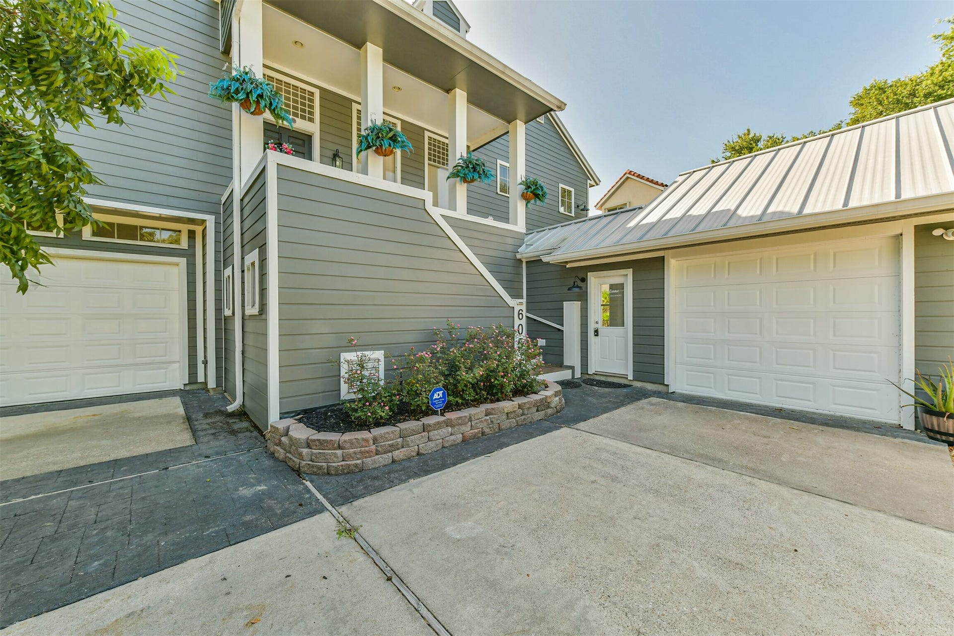 Modern gray facade, featuring dual garages and a welcoming entryway adorned with vibrant potted flowers.
