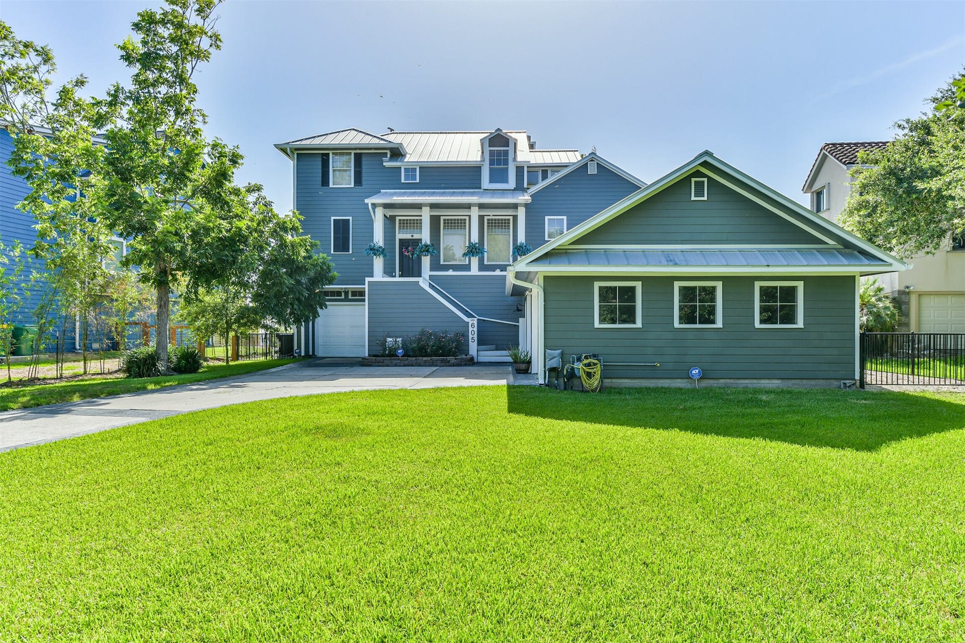 A beautiful two-story home with a welcoming front porch, surrounded by lush greenery and a spacious, well-maintained lawn.