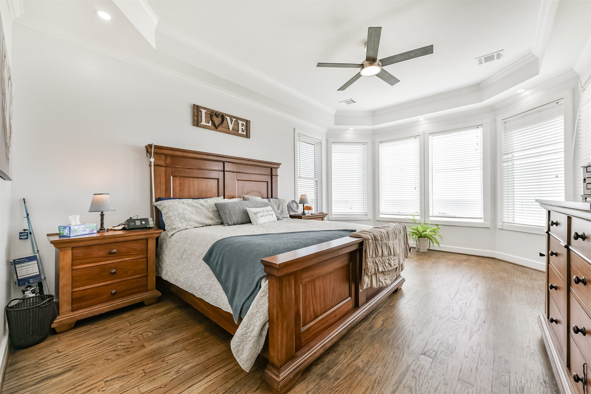 Bedroom featuring elegant hardwood floors, a large bay window with ample natural light, and classic wooden furniture for a warm, inviting atmosphere.
