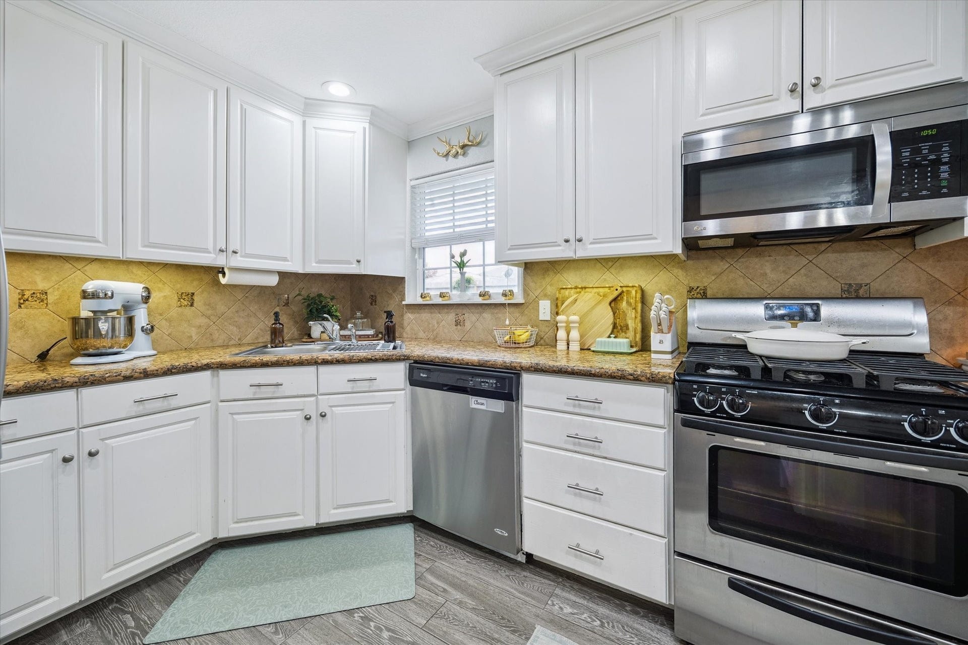 A corner window above the sink brings in extra light, while abundant cabinet space and undercabinet lighting enhance function and flow.
