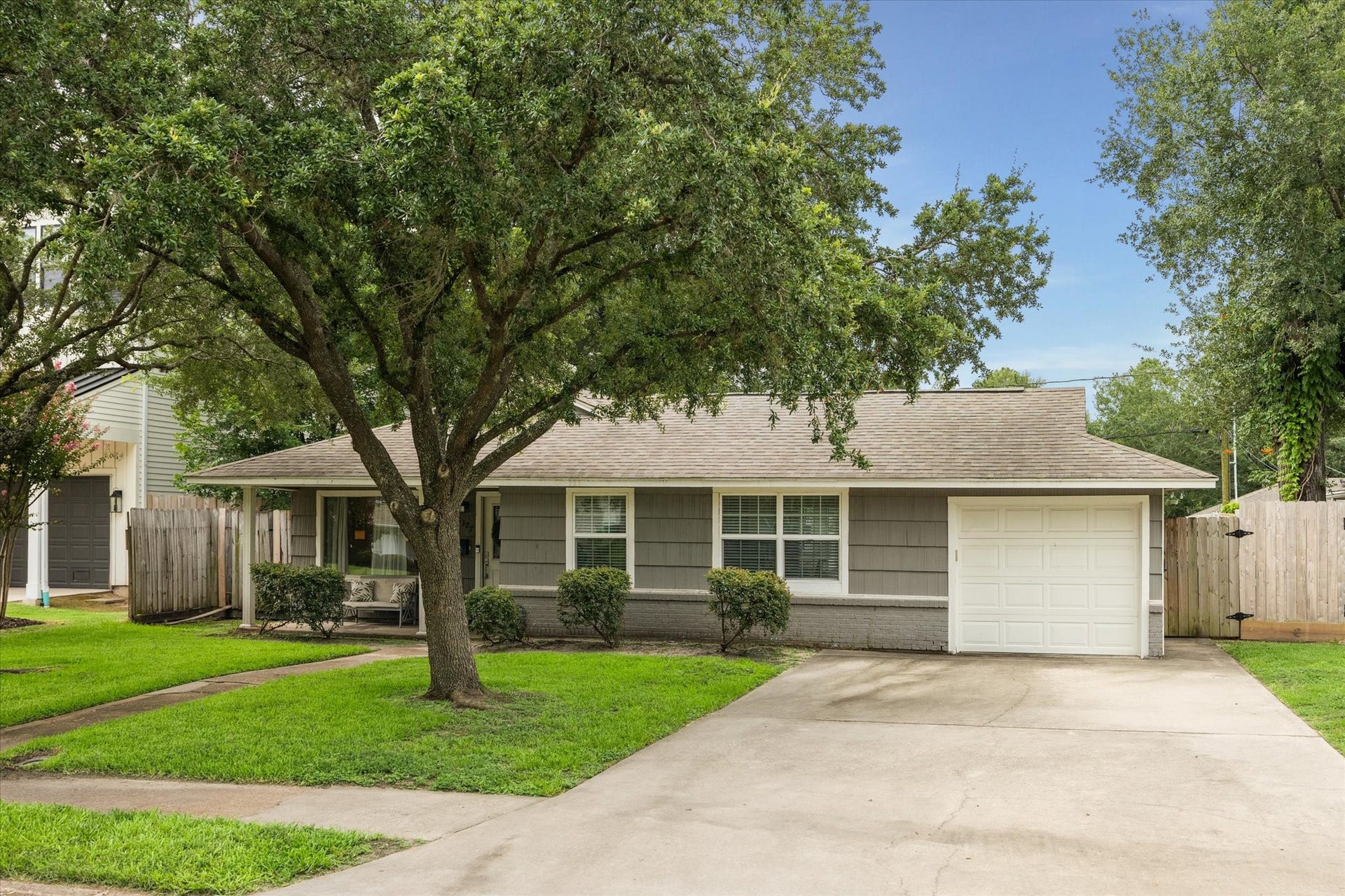 The extended driveway and attached single-car garage provide ample off-street parking in a quiet residential setting.