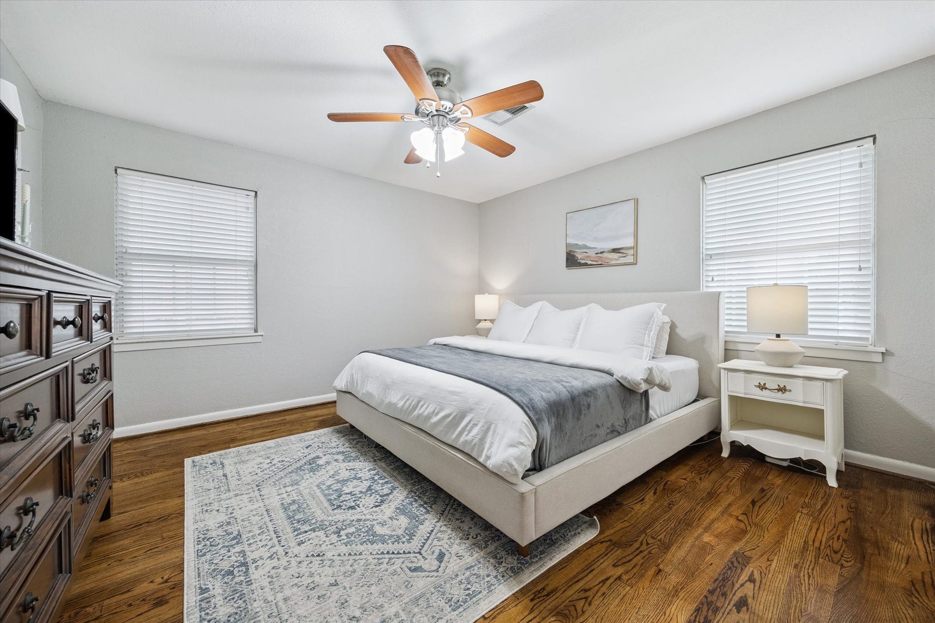 The primary bedroom features generous proportions, dual windows for natural light, and hardwood floors throughout.