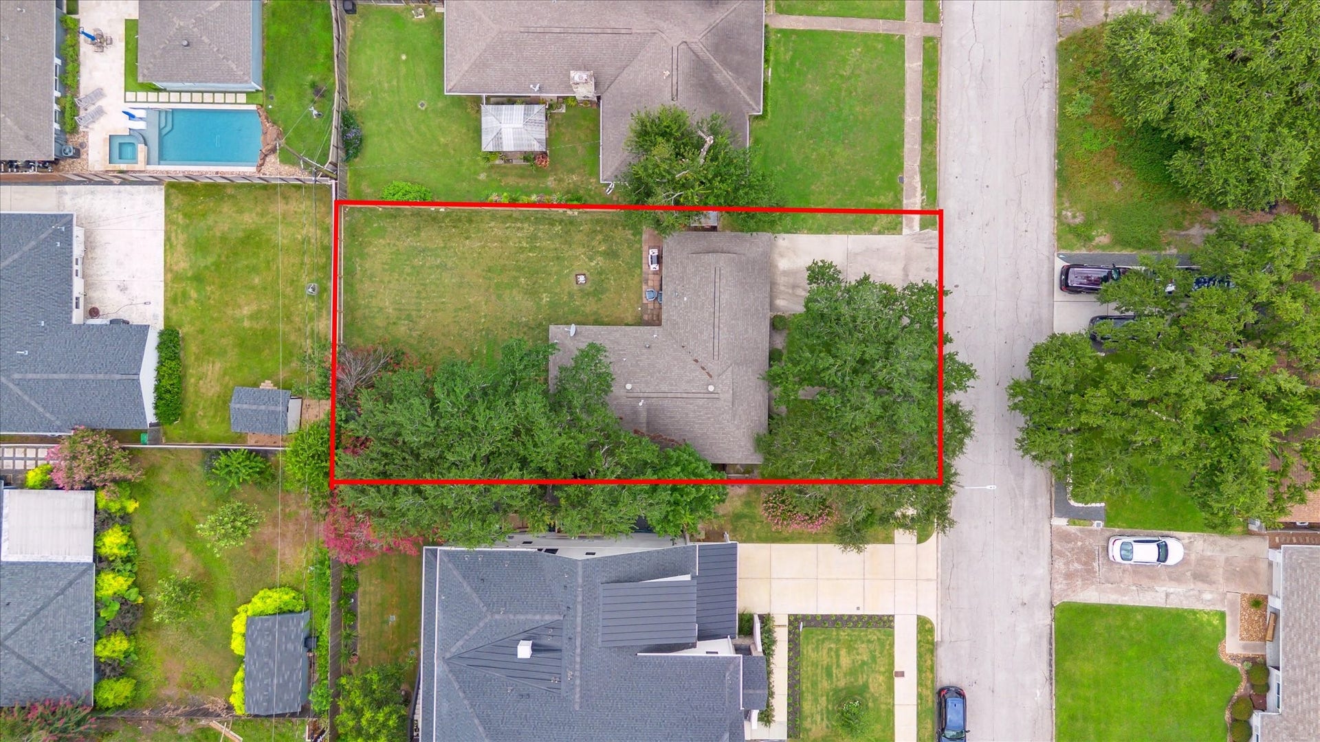 Aerial view reveals the oversized lot with a spacious backyard, mature trees, and patio area, offering room to relax, garden, or entertain.