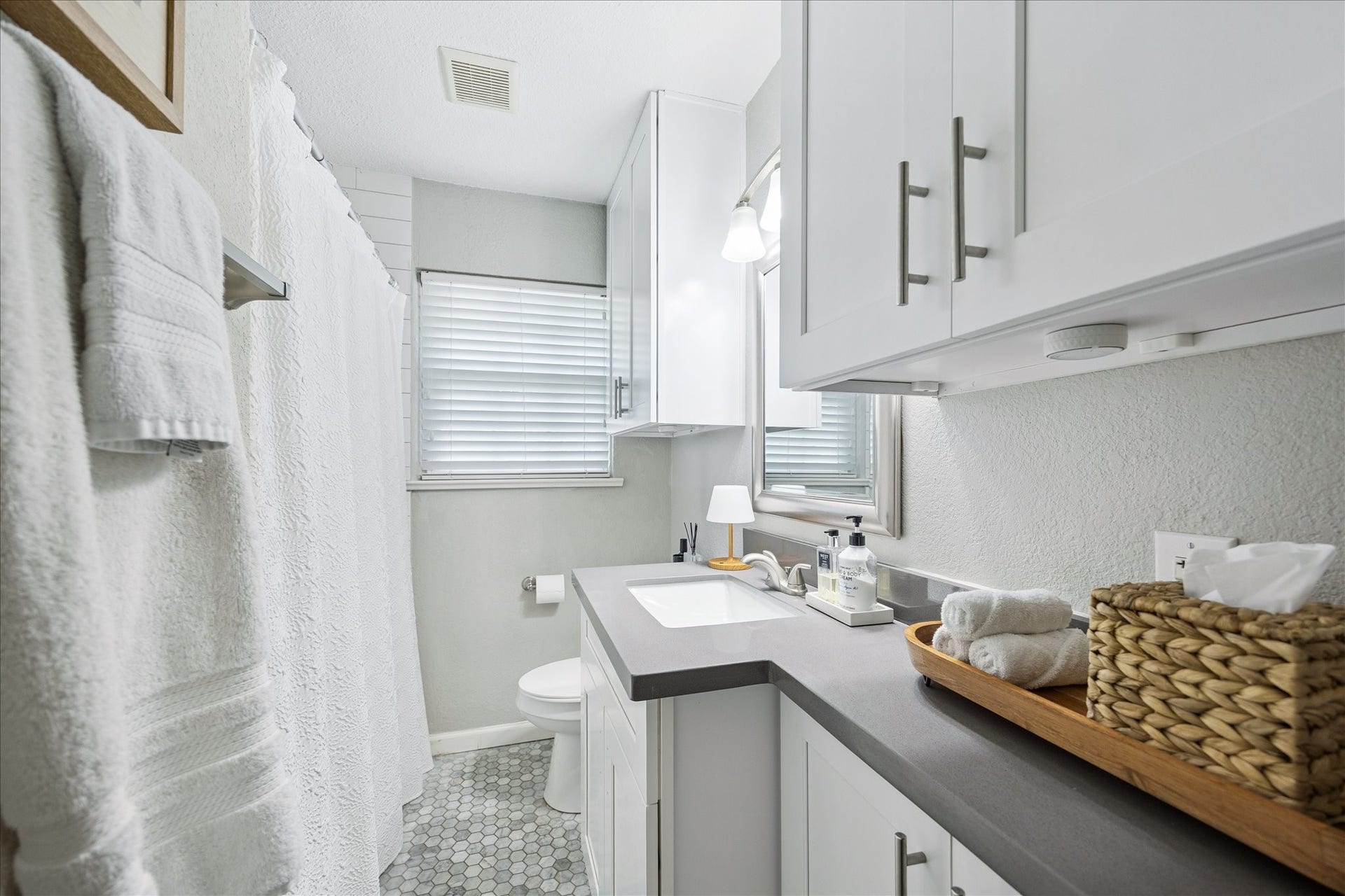 The full bathroom includes a sleek vanity with ample counter space, updated cabinetry, tile with modern fixtures.