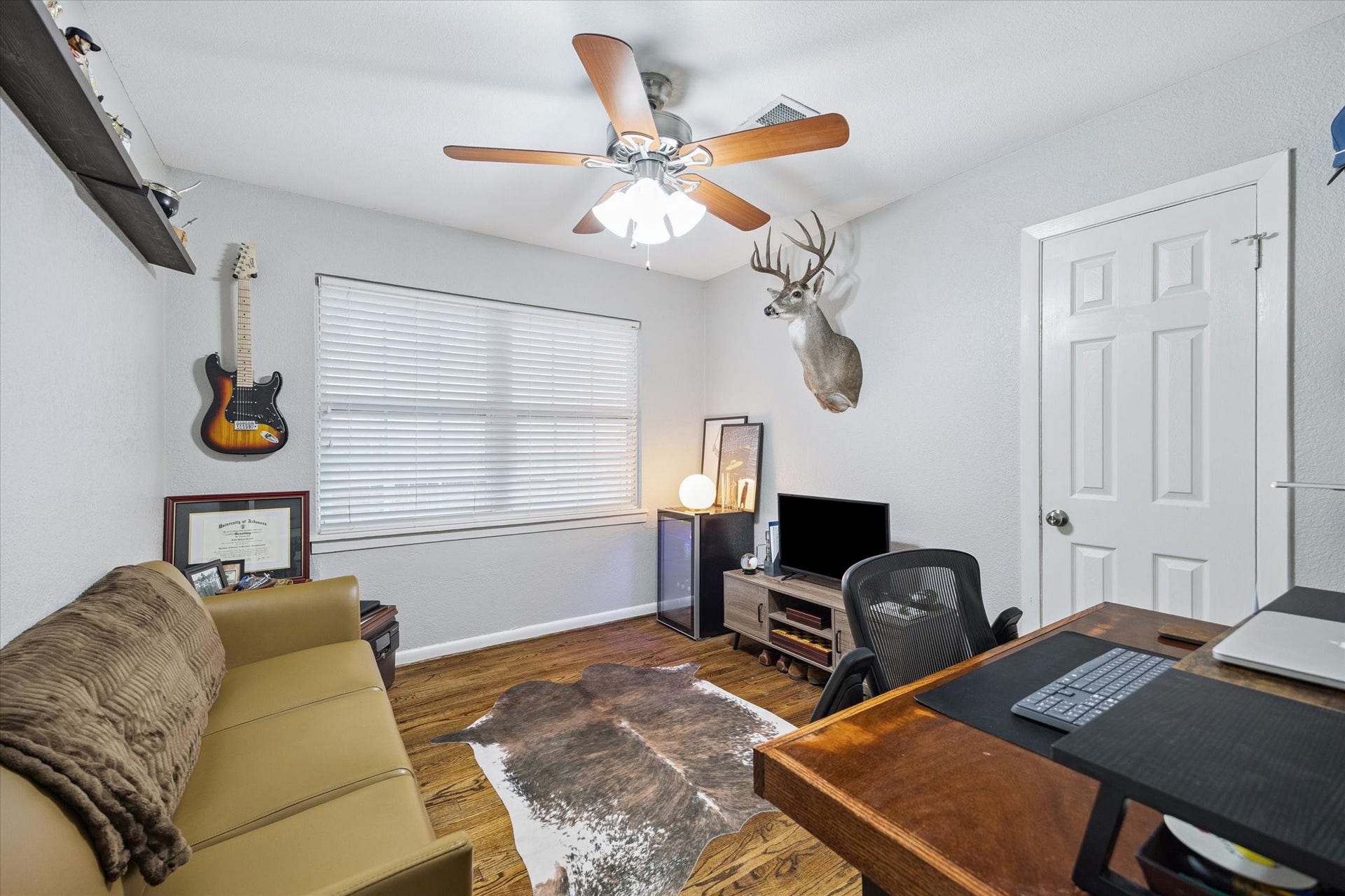 This third bedroom is currently styled as a home office and features hardwood flooring, a ceiling fan, and ample natural light.