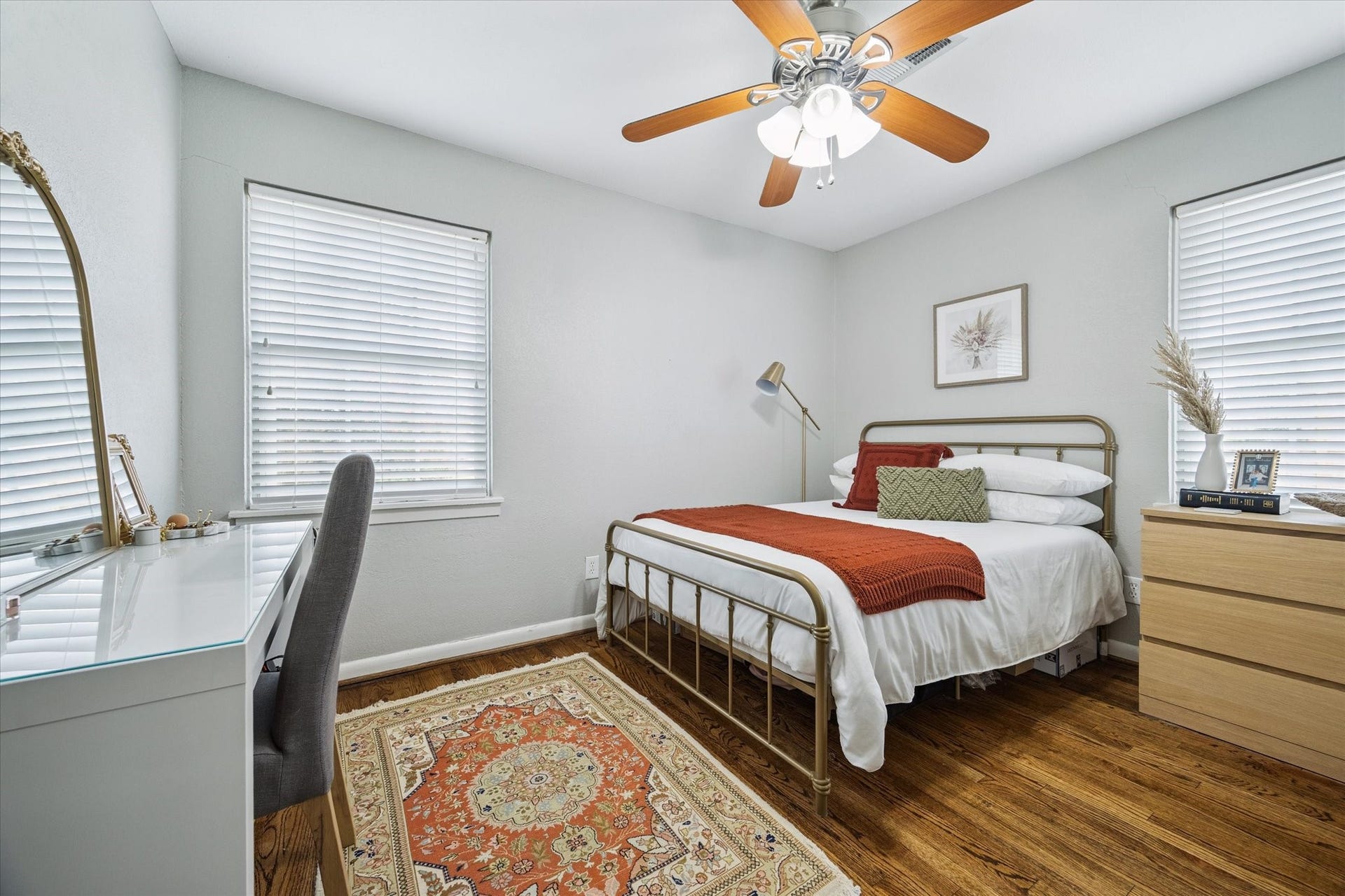 A secondary bedroom offers hardwood flooring, double windows, and space for a full-size bed plus a work or vanity area.