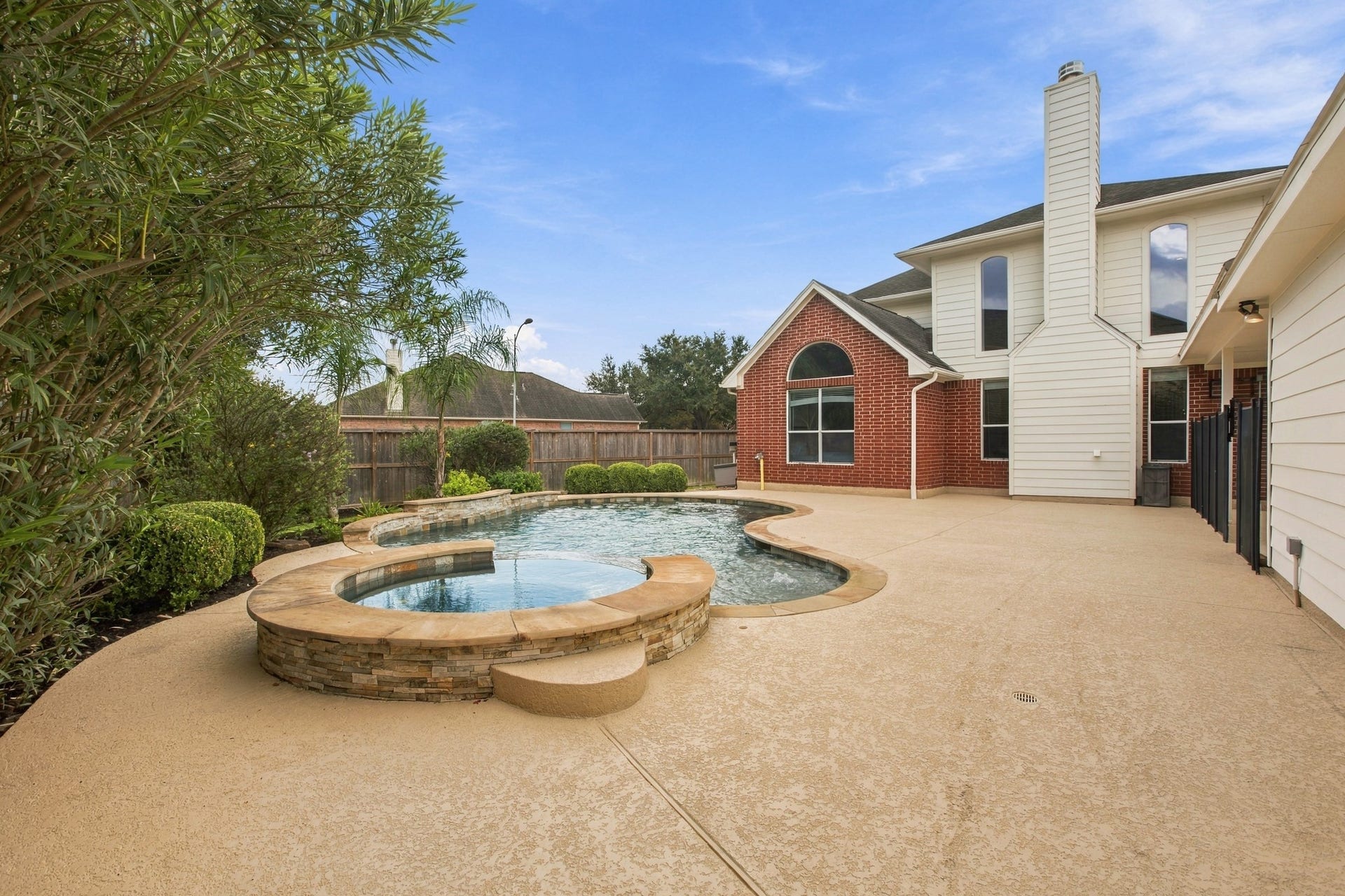 Backyard retreat featuring a sparkling pool and spa, expansive patio space, and plenty of room for outdoor entertaining.