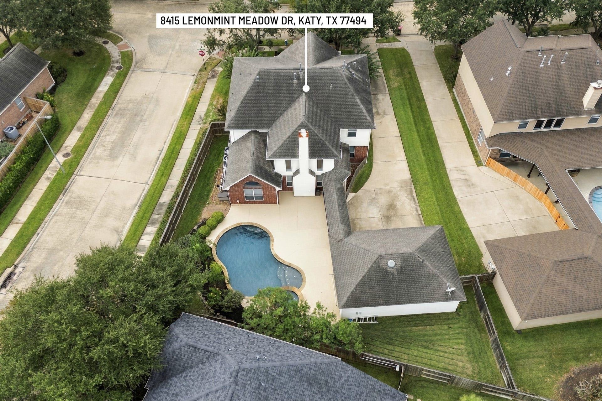 Bird's-eye view showcasing the home's corner lot, expansive driveway, detached garage, and backyard retreat with pool and spa.