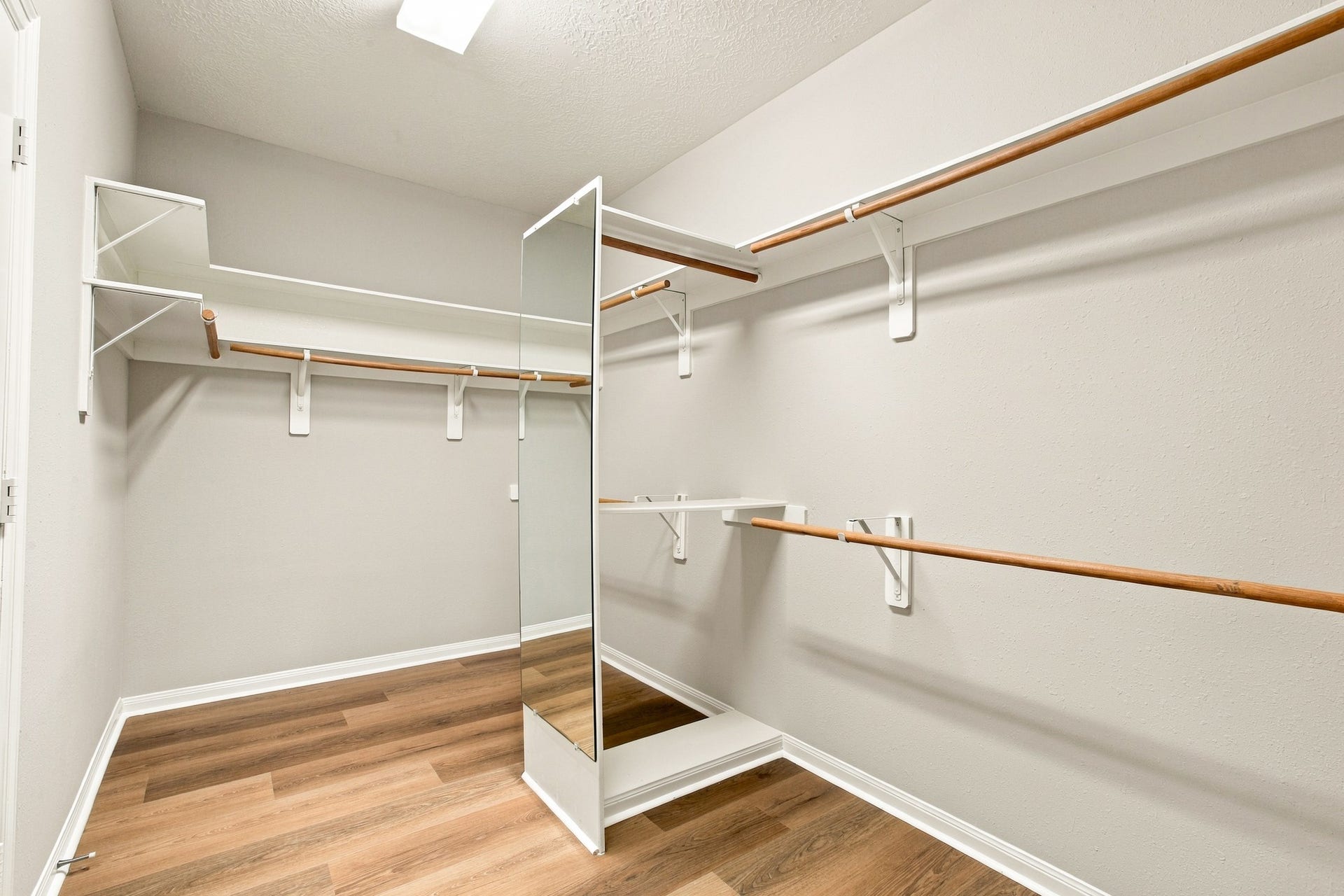 Primary walk-in closet featuring ample hanging space, built-in shelving, and a full-length mirror.