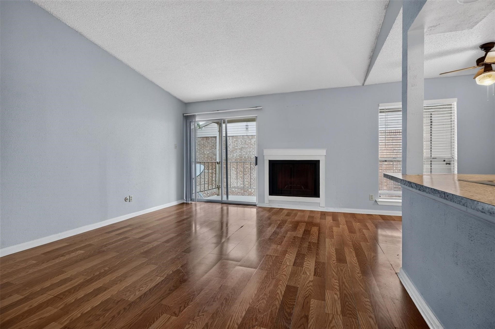 700 Thicket Lane, #304, Houston, TX 77079 Spacious living area with elegant wood flooring, featuring a cozy fireplace and abundant natural light from large sliding doors leading to a private balcony.