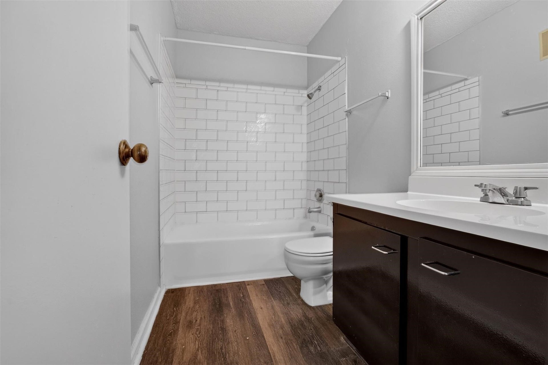700 Thicket Lane, #304, Houston, TX 77079 Modern bathroom featuring a sleek vanity, stylish subway tile, and elegant wood-look flooring.