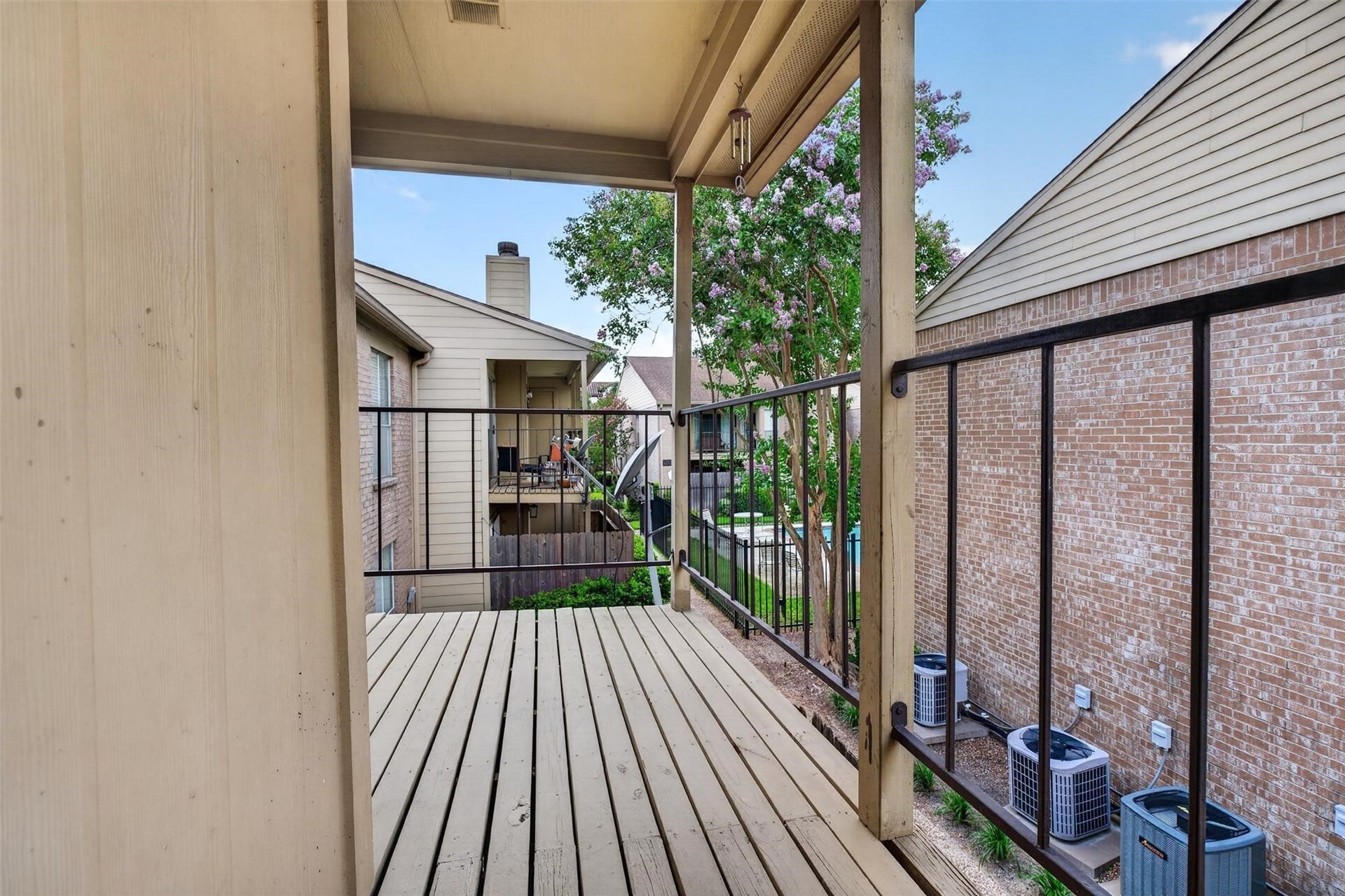700 Thicket Lane, #304, Houston, TX 77079 Charming balcony with a cozy wooden deck, offering views of neighboring homes and lush greenery, perfect for relaxation.