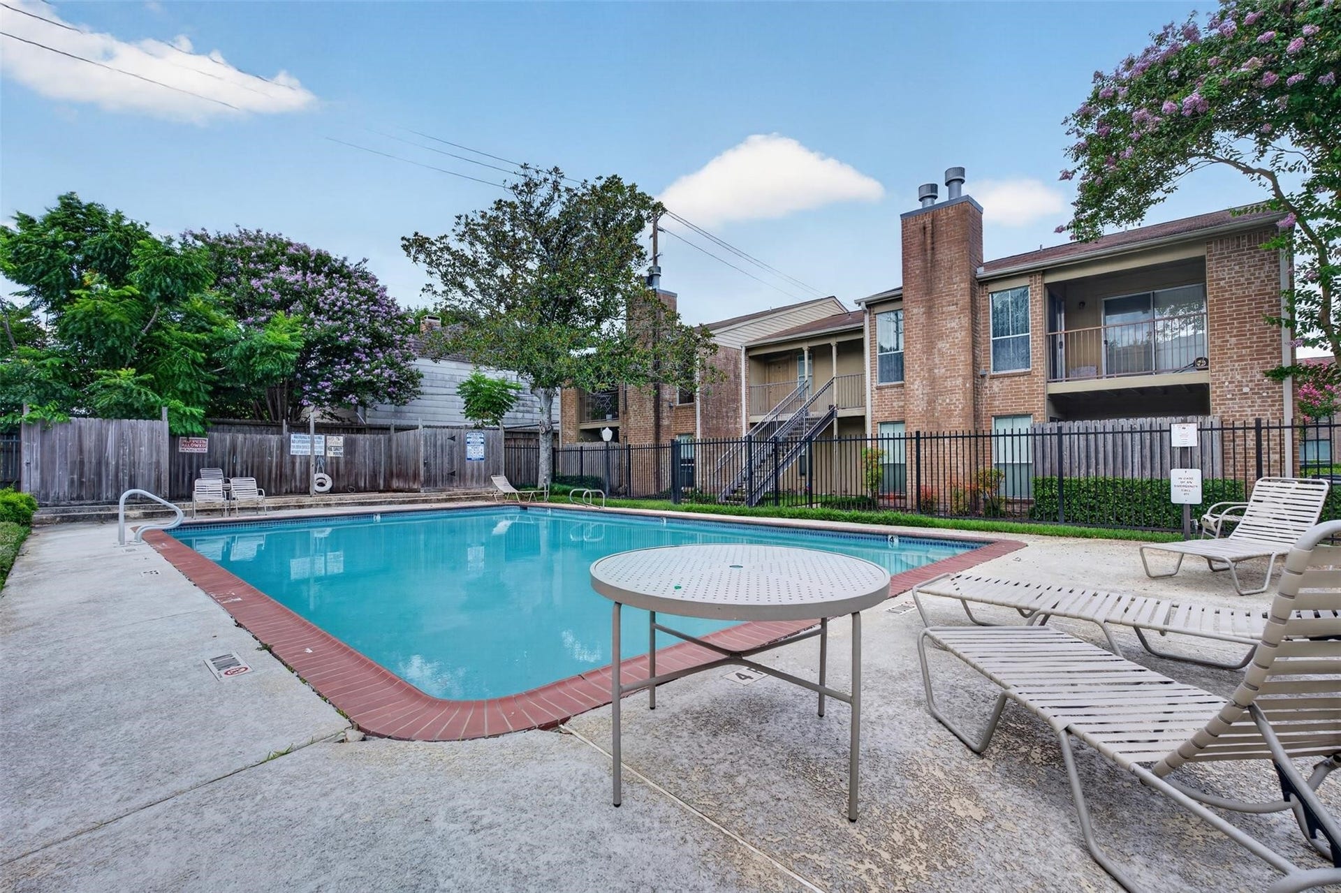 700 Thicket Lane, #304, Houston, TX 77079 Relax in this inviting community pool area, surrounded by lush greenery and comfortable lounge chairs, perfect for unwinding on sunny days.
