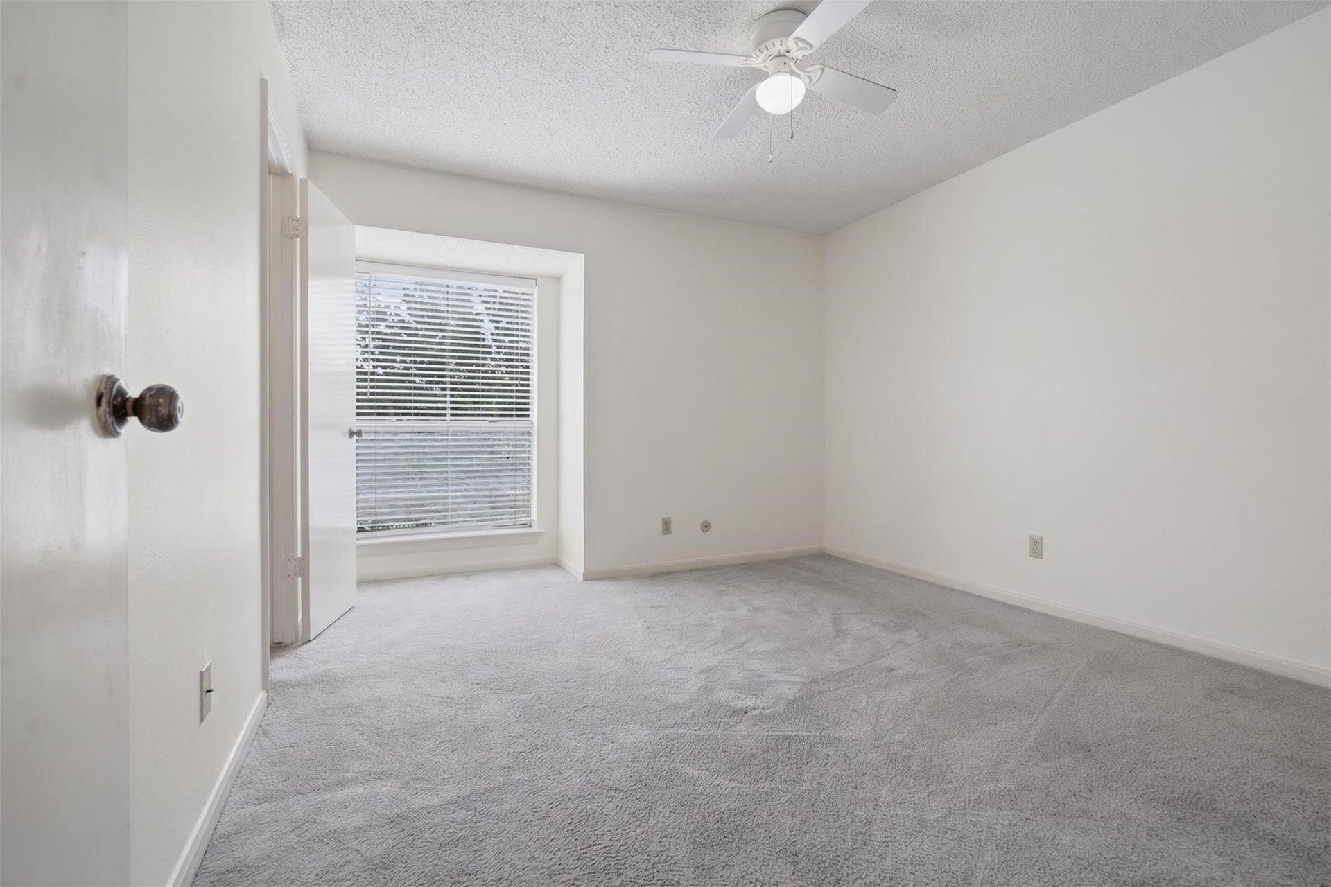 700 Thicket Lane, #304, Houston, TX 77079 Bright and airy bedroom featuring a large window with blinds, plush carpet, and a ceiling fan for comfort.