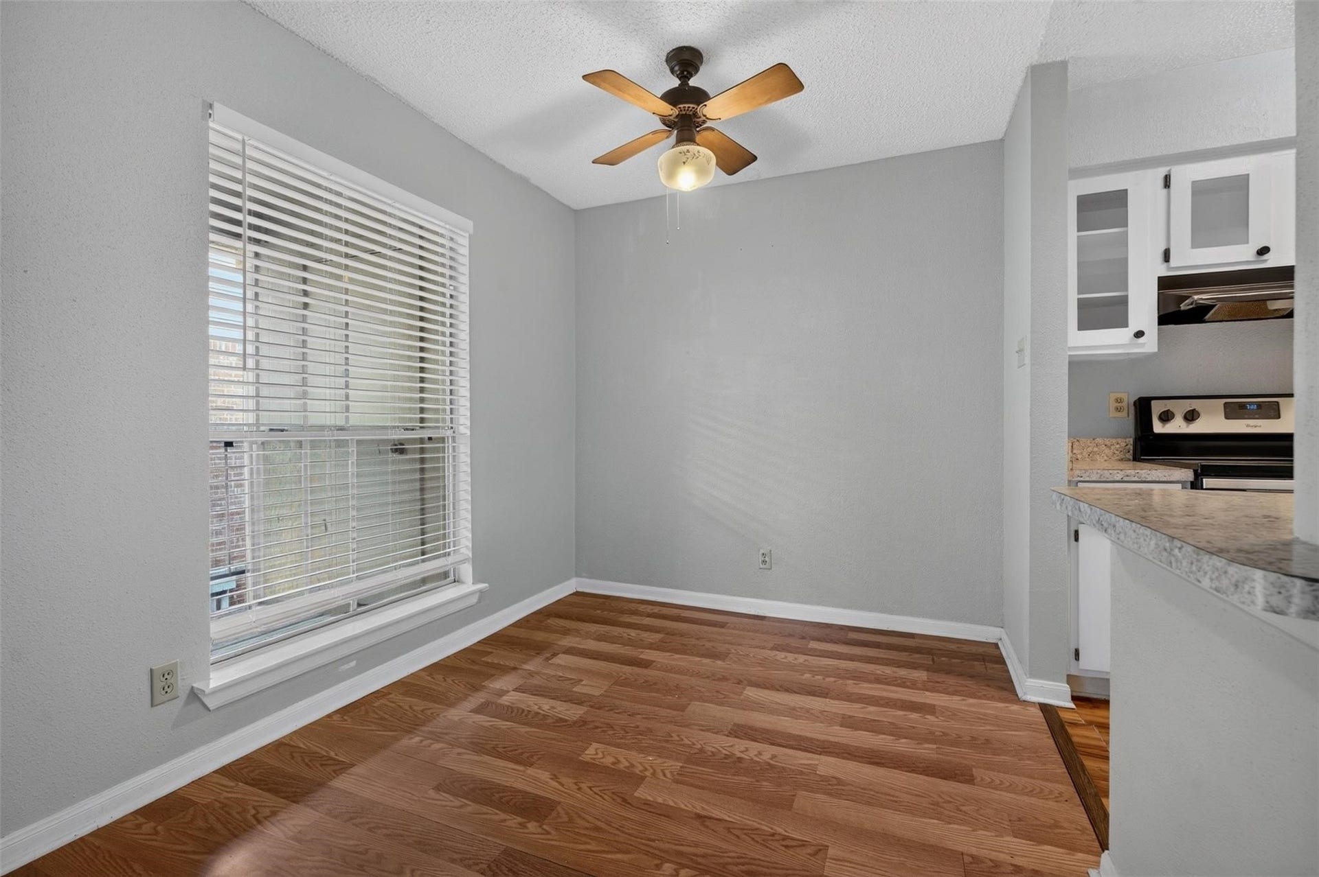700 Thicket Lane, #304, Houston, TX 77079 Charming dining area with warm hardwood floors, abundant natural light from a large window, and a cozy ceiling fan. Adjacent to a modern kitchen featuring sleek countertops and updated appliances.