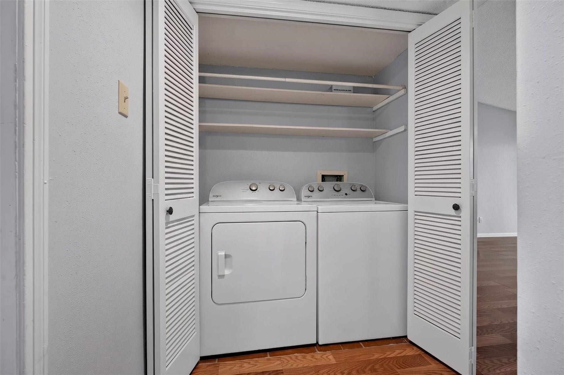 700 Thicket Lane, #304, Houston, TX 77079 Convenient laundry closet with washer and dryer, featuring louvered doors and built-in shelving for storage solutions.