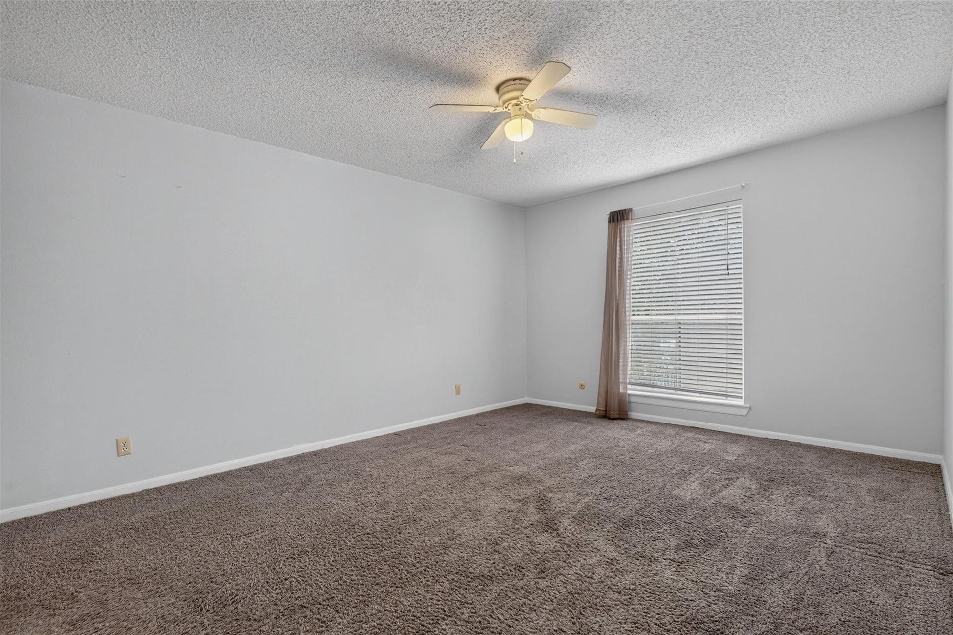 700 Thicket Lane, #304, Houston, TX 77079 Spacious bedroom with soft carpet, neutral walls, and abundant natural light from a large window, complemented by a ceiling fan for comfort.
