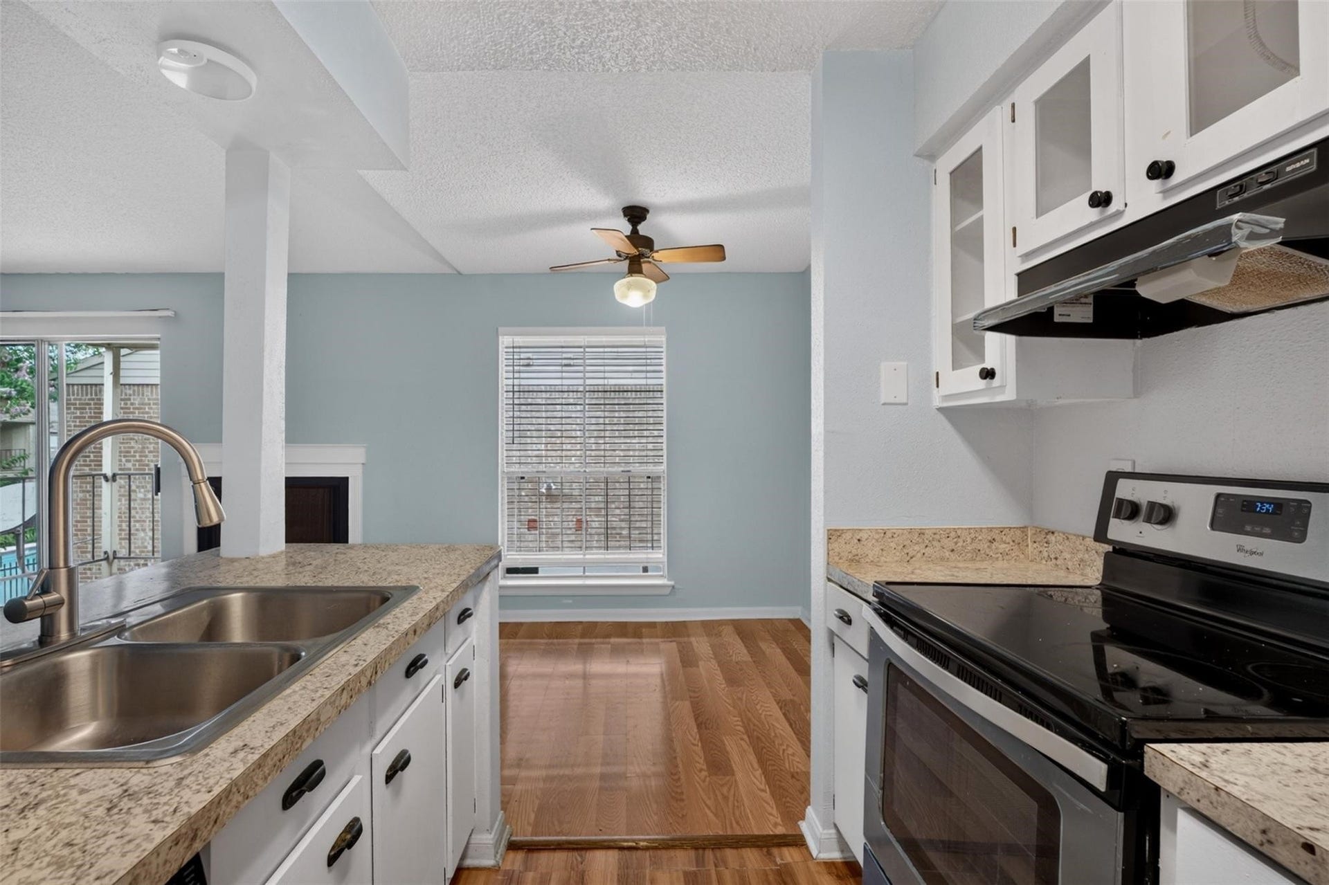 700 Thicket Lane, #304, Houston, TX 77079 Charming kitchen with sleek granite countertops, modern appliances, and ample natural light from the adjacent dining area featuring a stylish ceiling fan.