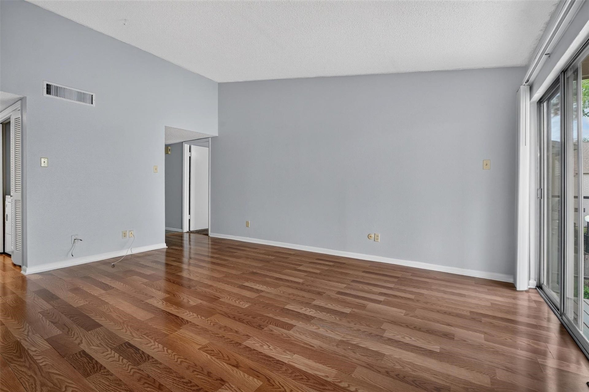 700 Thicket Lane, #304, Houston, TX 77079 Spacious living area with hardwood floors and large sliding glass doors, offering ample natural light and a seamless indoor-outdoor connection.