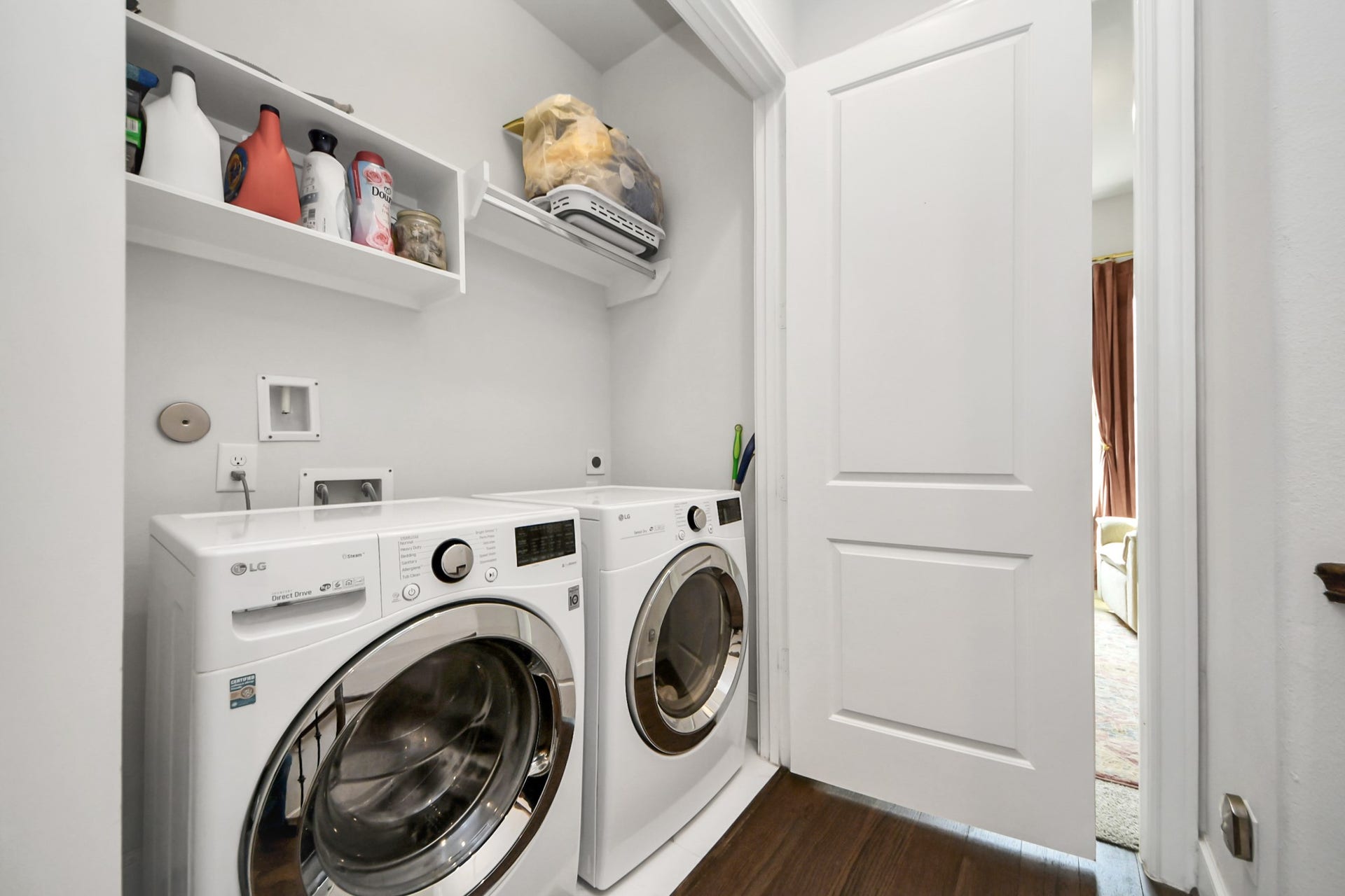 Convenient laundry closet equipped with modern LG washer and dryer, complemented by overhead shelving for extra storage.