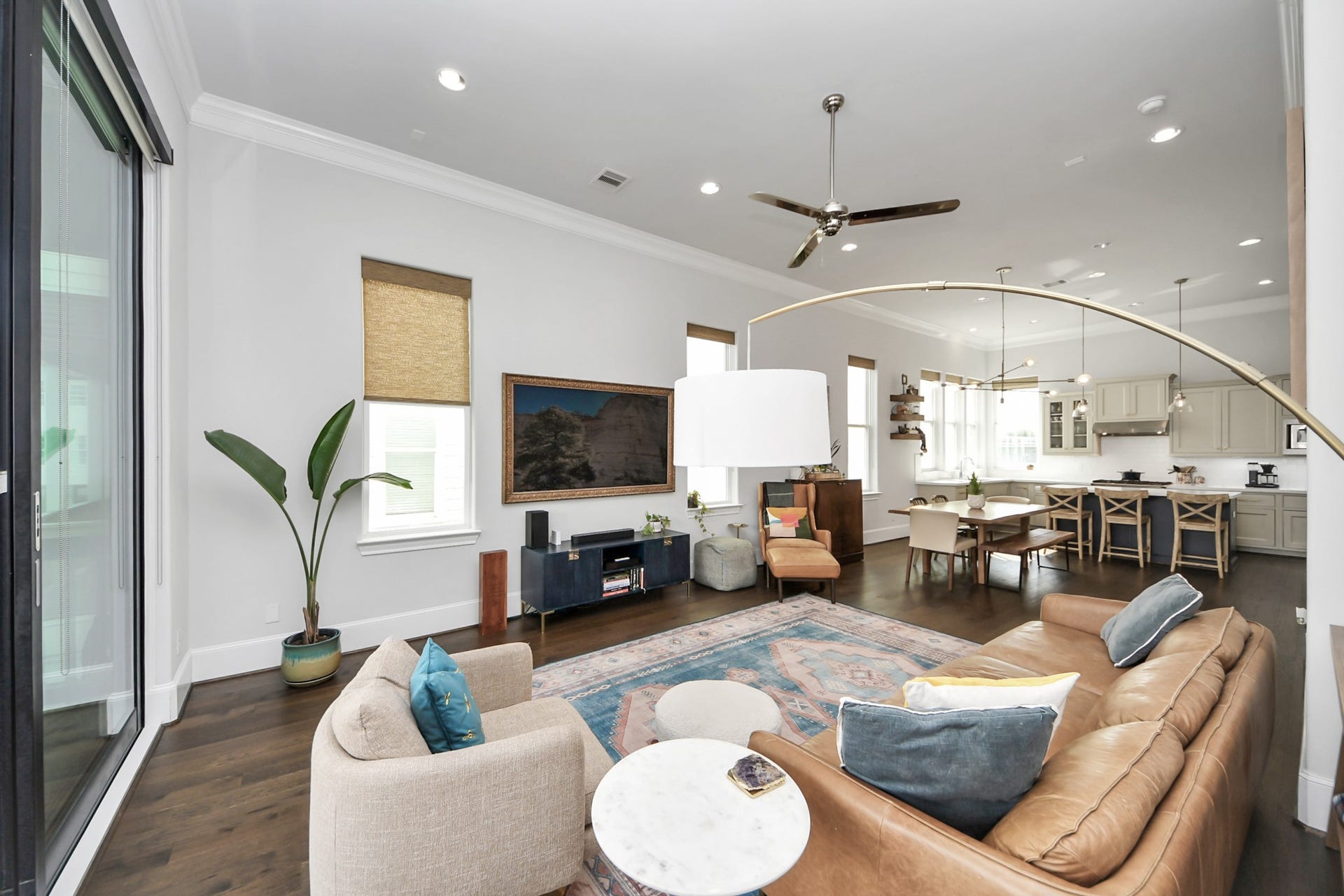 Spacious open-concept living area featuring a modern kitchen with a large island, cozy seating, elegant lighting, and expansive windows for ample natural light.
