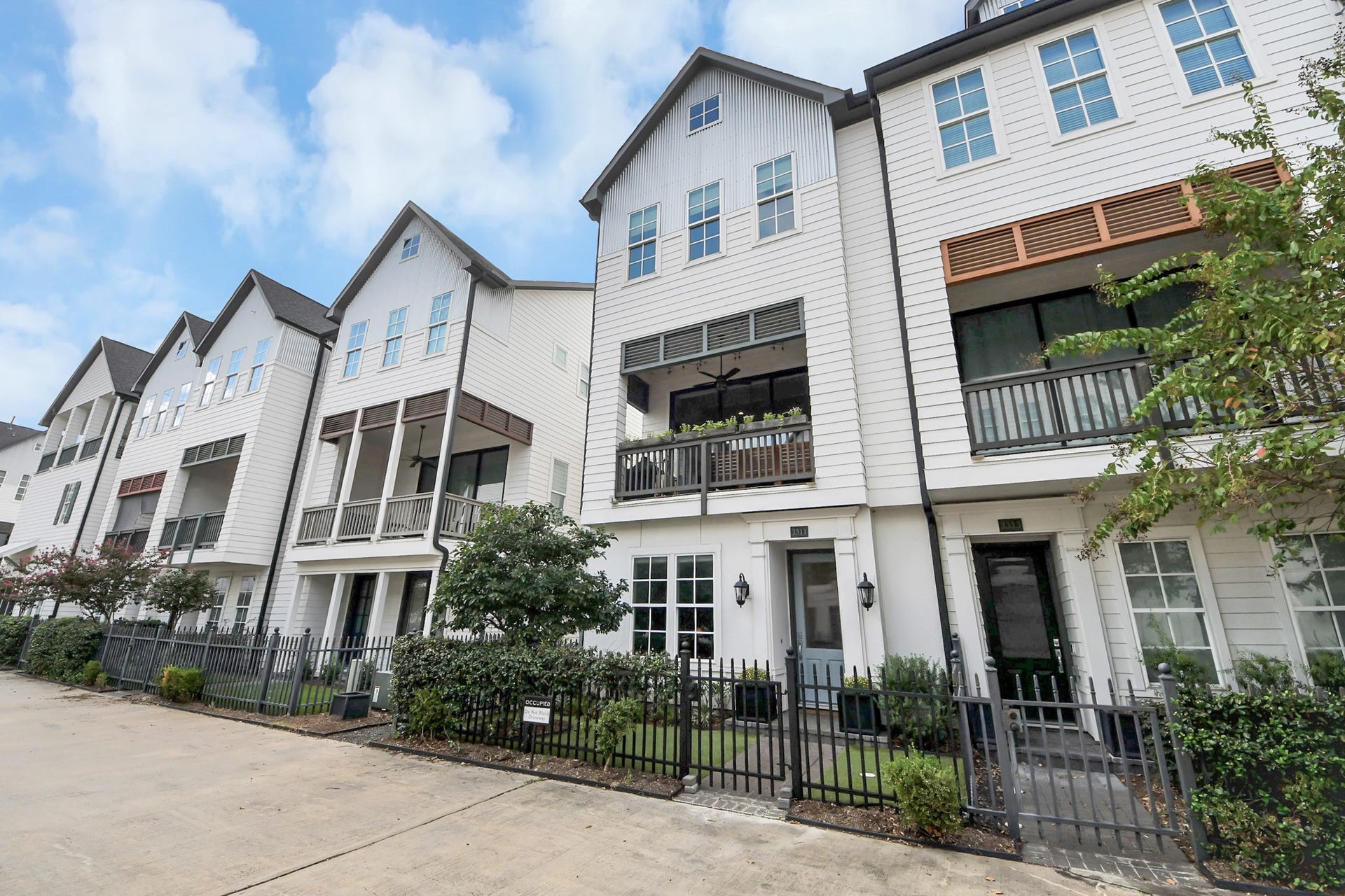 Charming row of modern townhouses with inviting balconies, stylish exteriors, and a neatly landscaped front.