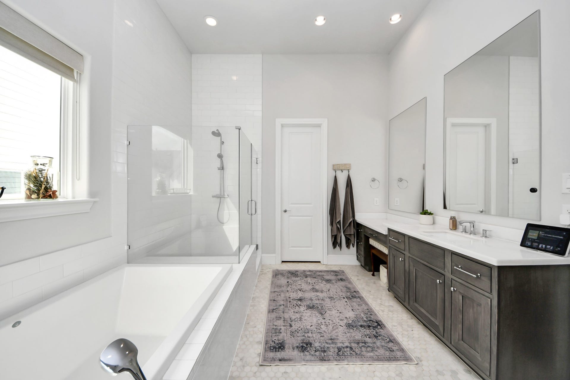 Sleek and modern bathroom featuring a spacious glass-enclosed shower, a luxurious soaking tub, and dual-sink vanity with ample storage.