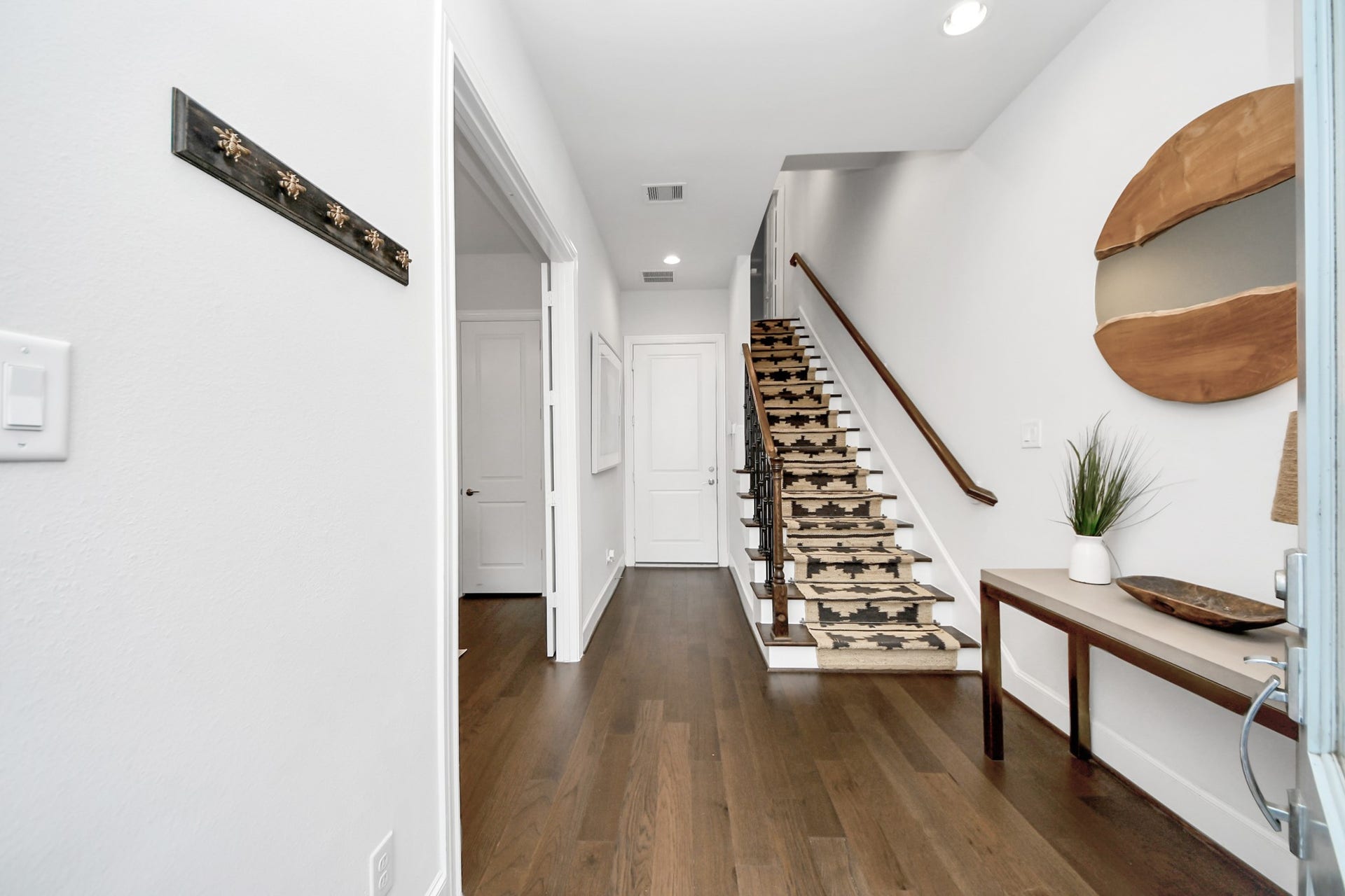 Inviting entryway with elegant wood flooring, a stylishly decorated staircase, and modern accents, offering a warm welcome.