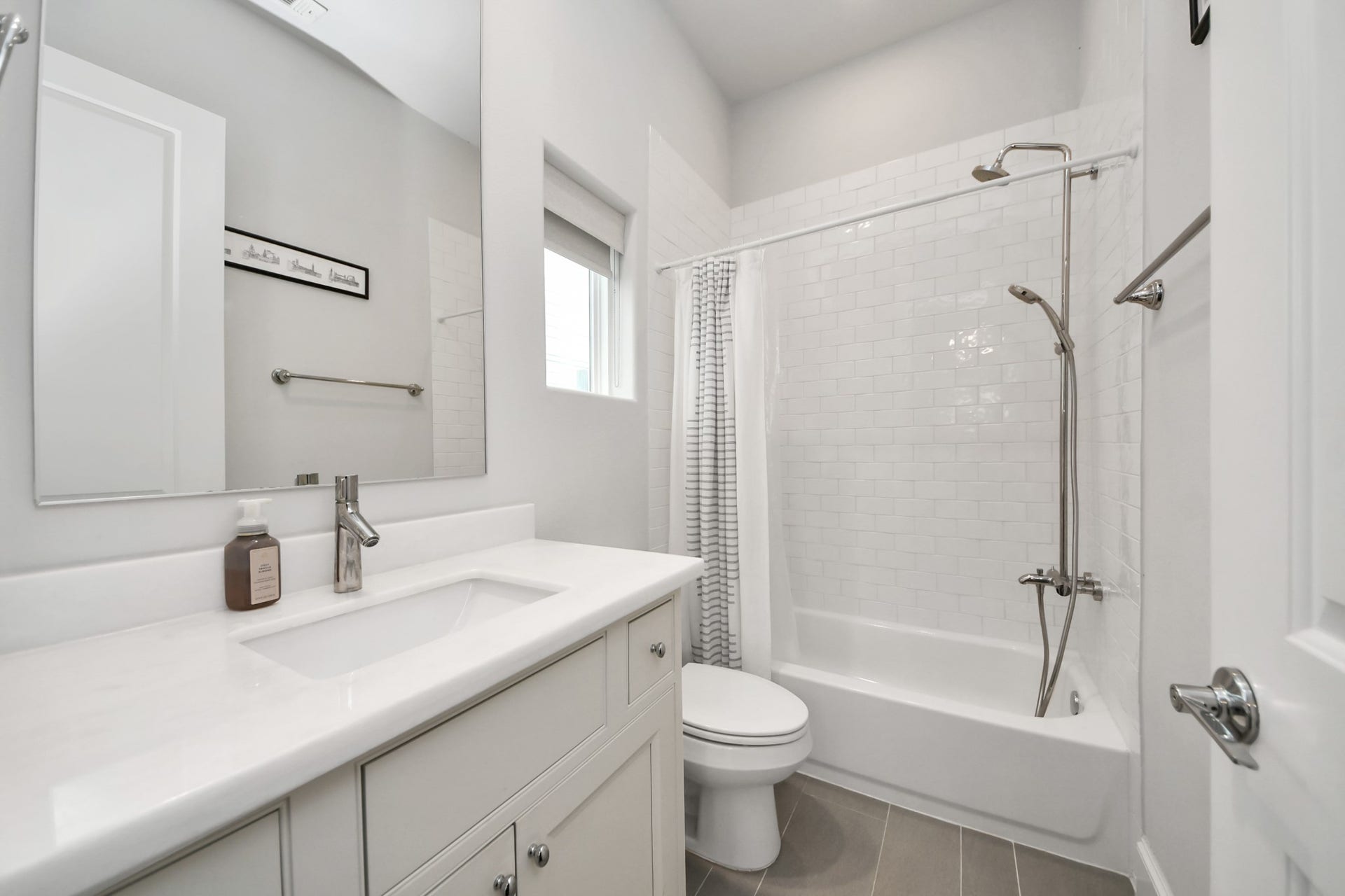 Bright and modern bathroom featuring a sleek vanity with ample storage, complemented by a classic white subway tile shower and tub combination.