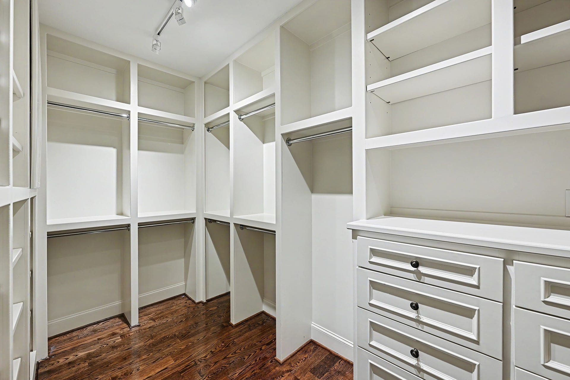 One of two primary suite walk-in closets, featuring extensive built-in cabinetry and ample hanging space for clothing, shoes, and accessories.