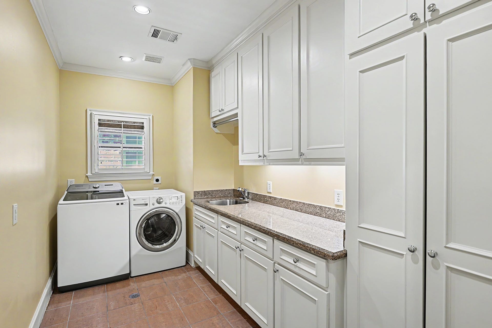 Second floor utility room has a large folding counter, laundry sink, and built-in storage.