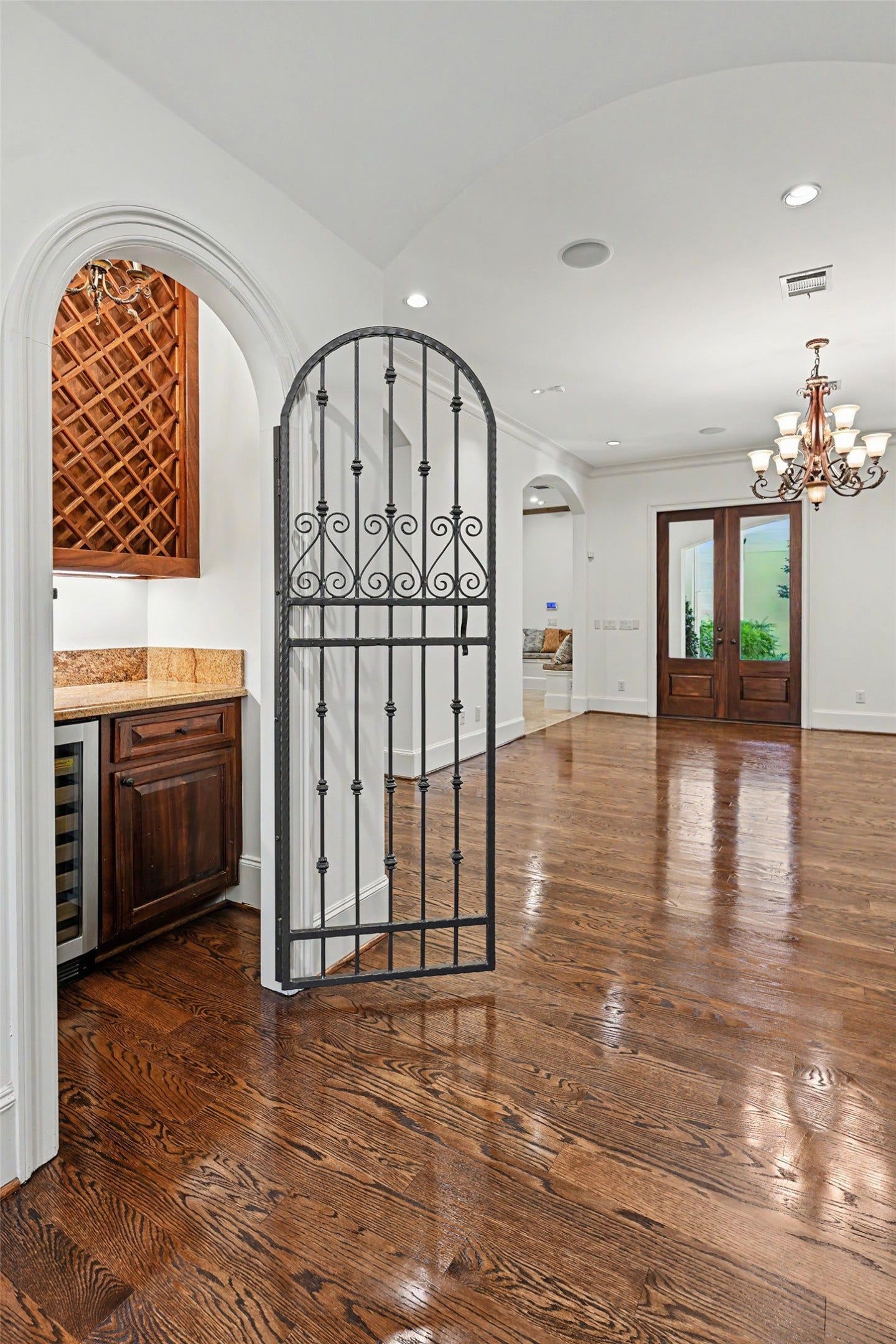 The wine room features a wrought-iron gate, built-in bottle storage, a wine refrigerator, ample cabinetry, and a serving counter.