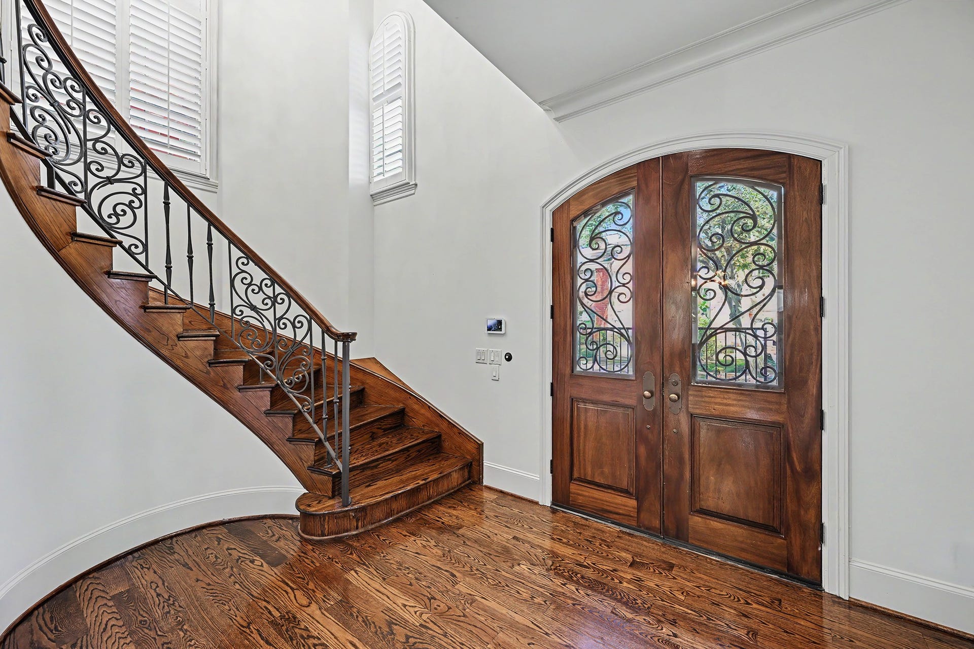 A graceful curved solid-oak staircase echoes the front doors wrought-iron detailing, while windows fill the space with natural light.