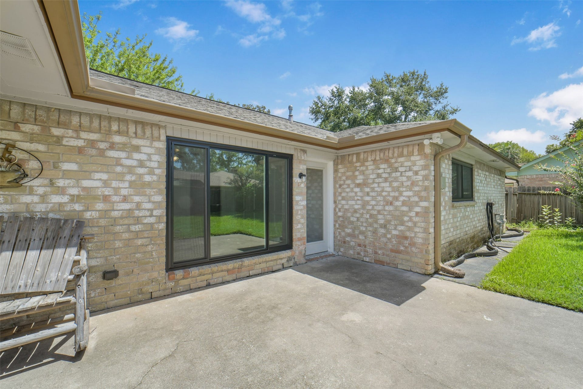Relaxing patio with sliding glass doors leading to the backyard, complemented by brick exterior and a spacious concrete slab  perfect for outdoor dining, entertaining, or simply unwinding.