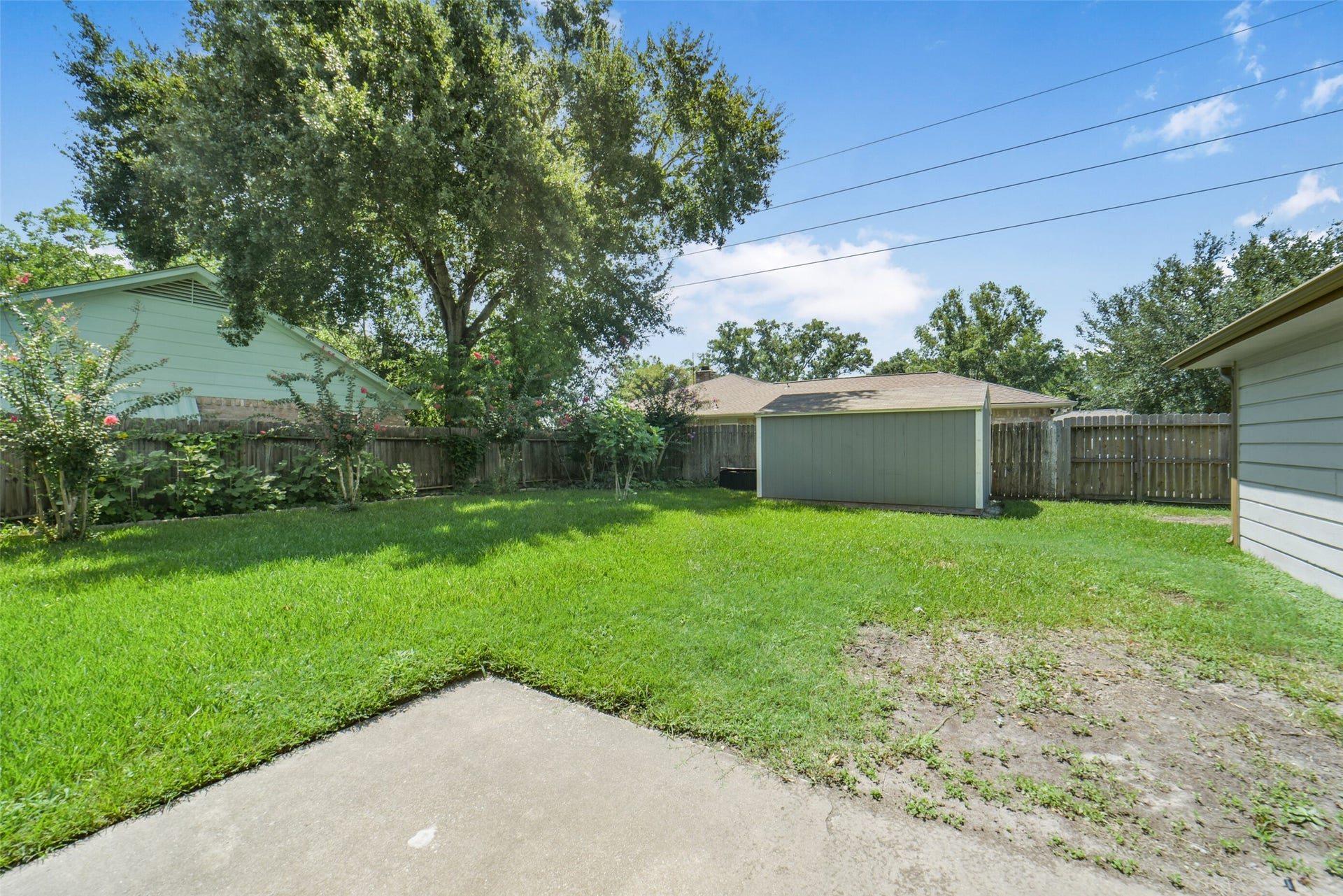 Spacious fully fenced backyard, blooming shrubs, and a storage shed, plenty of room for outdoor entertaining, play, or gardening in a private, tranquil setting.