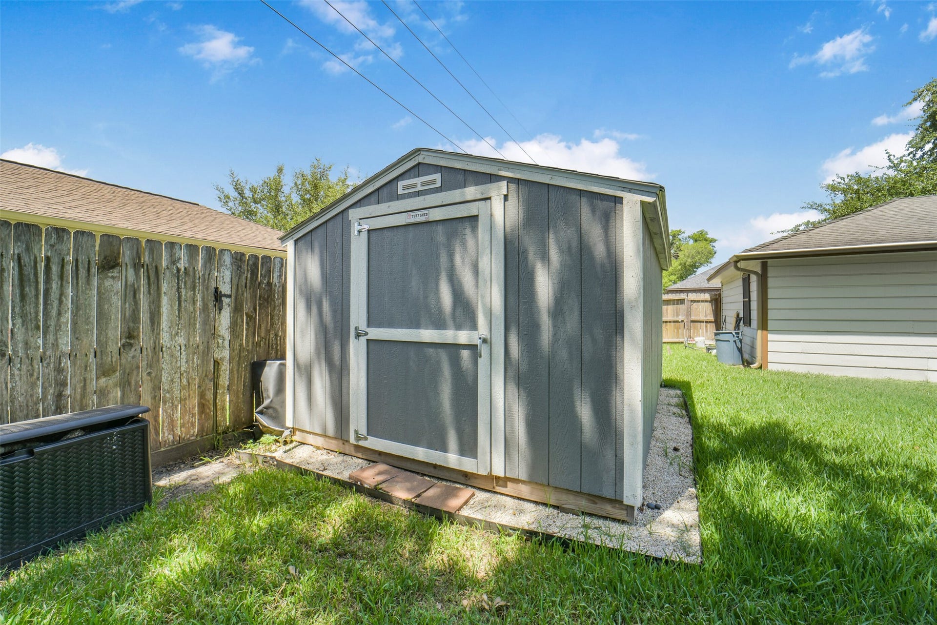 Handy backyard storage shed offering extra space for tools, equipment, or outdoor gear, set within a fully fenced yard with lush grass  great added functionality for the property.