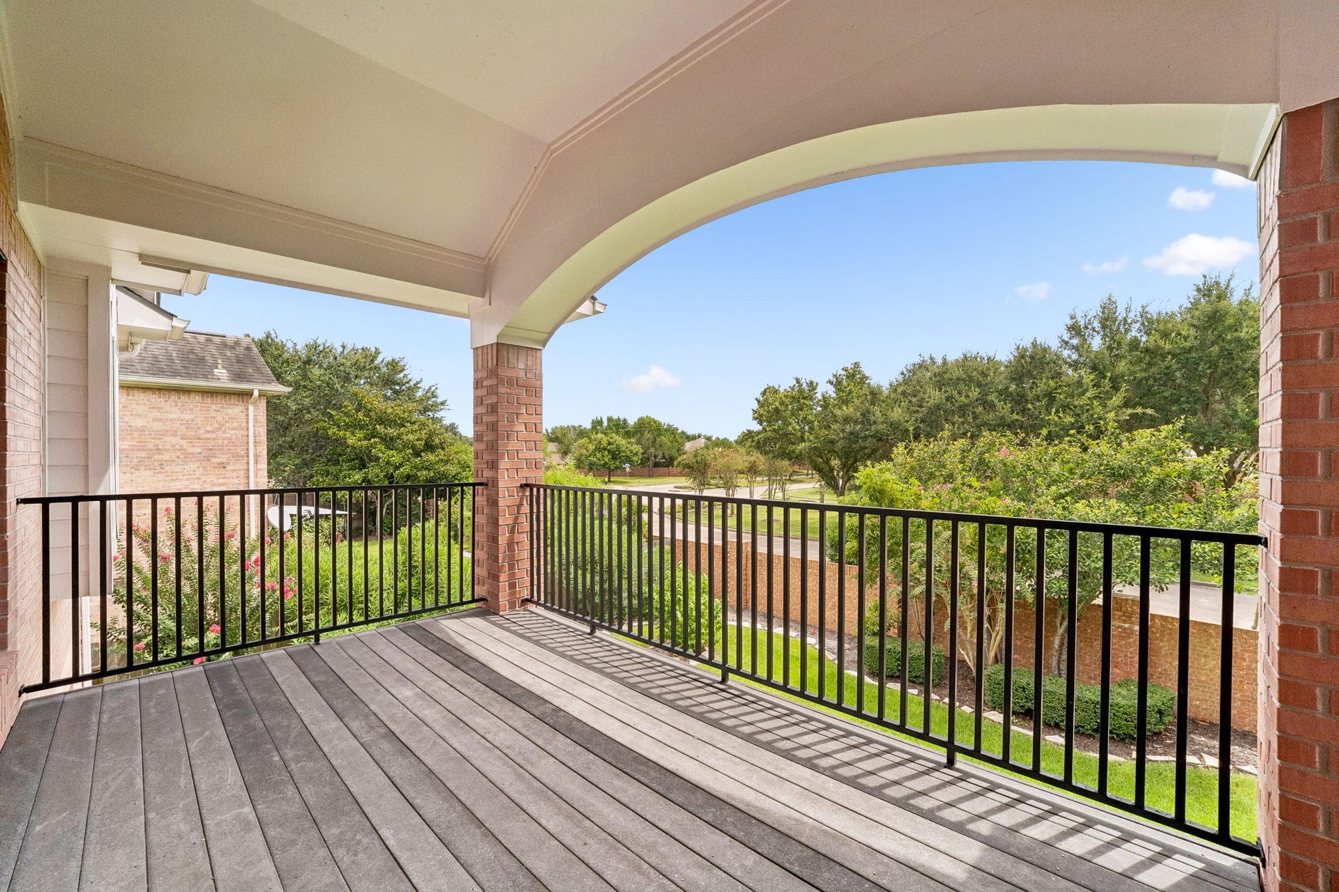 Spacious covered balcony with elegant archway and serene views of lush greenery, perfect for relaxing or entertaining.