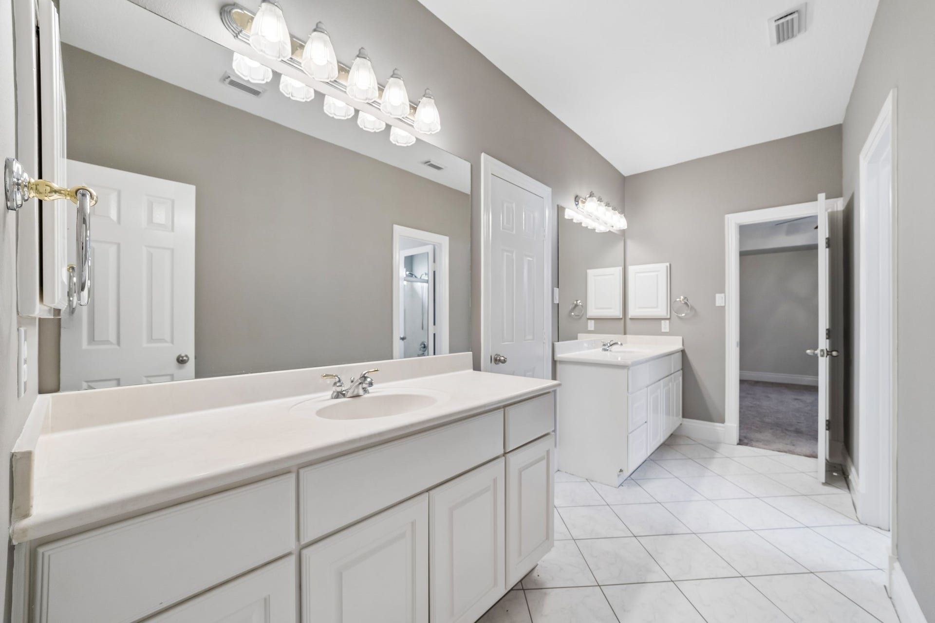 Spacious Jack-and-Jill bathroom featuring dual vanities, expansive mirrors, generous counter space, and convenient access between the adjoining bedrooms.