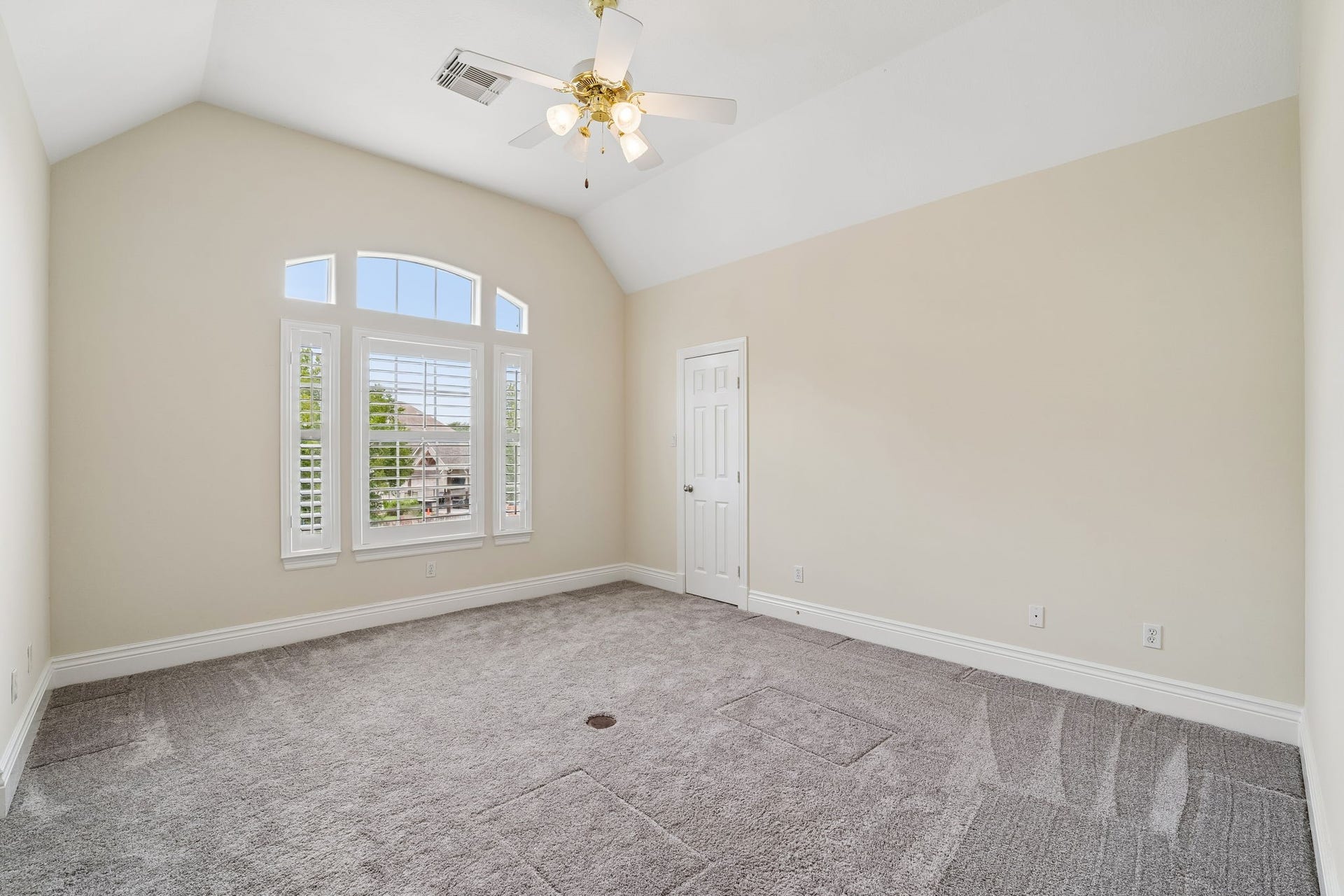 Spacious third bedroom#4 featuring a vaulted ceiling, ceiling fan, plush carpeting, large windows with plantation shutters, and a private closet.