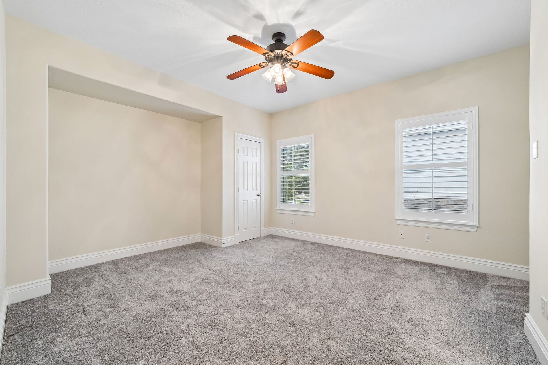 Spacious second-floor bedroom#3 featuring plush carpeting, a ceiling fan, and two windows with plantation shutters that brings in abundant natural light.