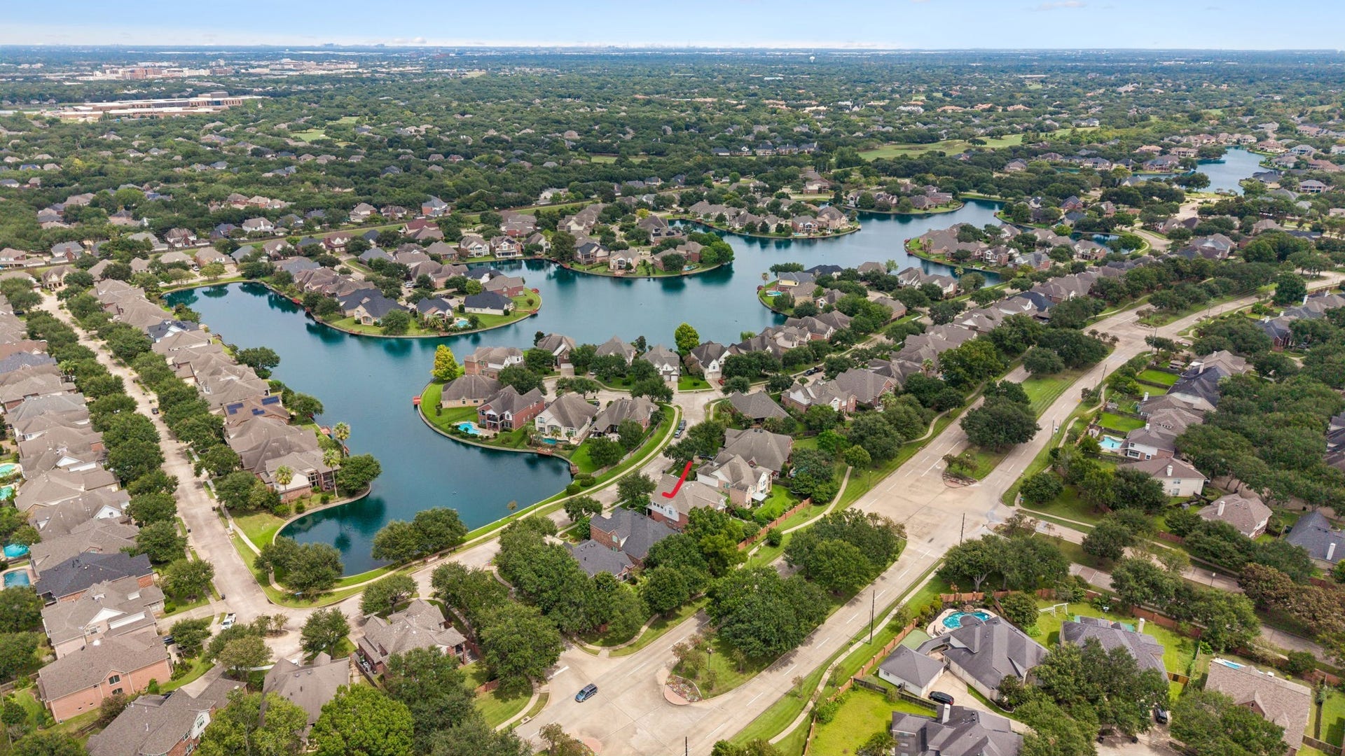 Charming suburban neighborhood with tree-lined streets and well-maintained homes, adjacent to lush green spaces and a serene lake.