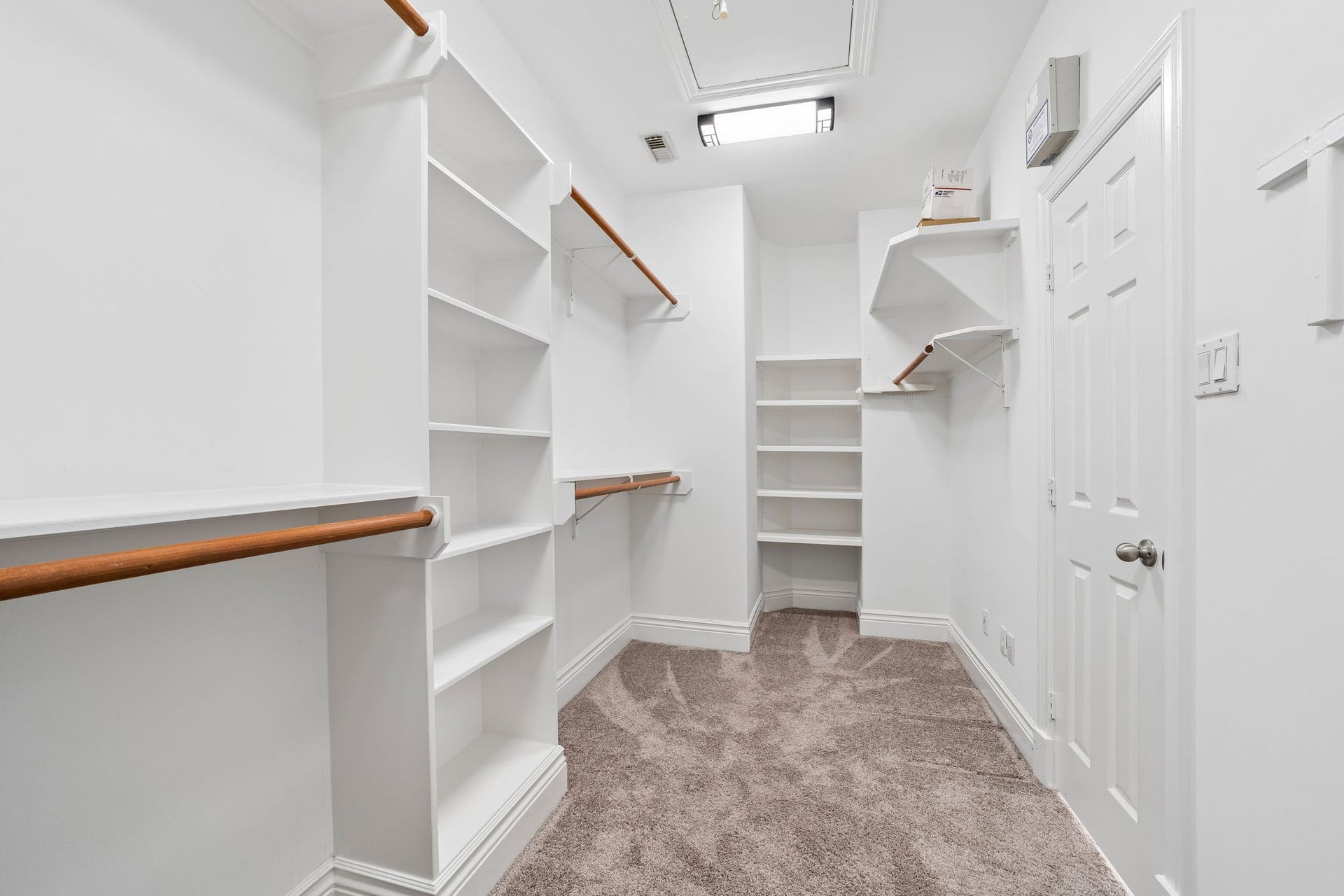 Spacious primary walk-in closet featuring extensive built-in shelving, multiple hanging areas, and plenty of room for organized clothing, shoes, and accessories.