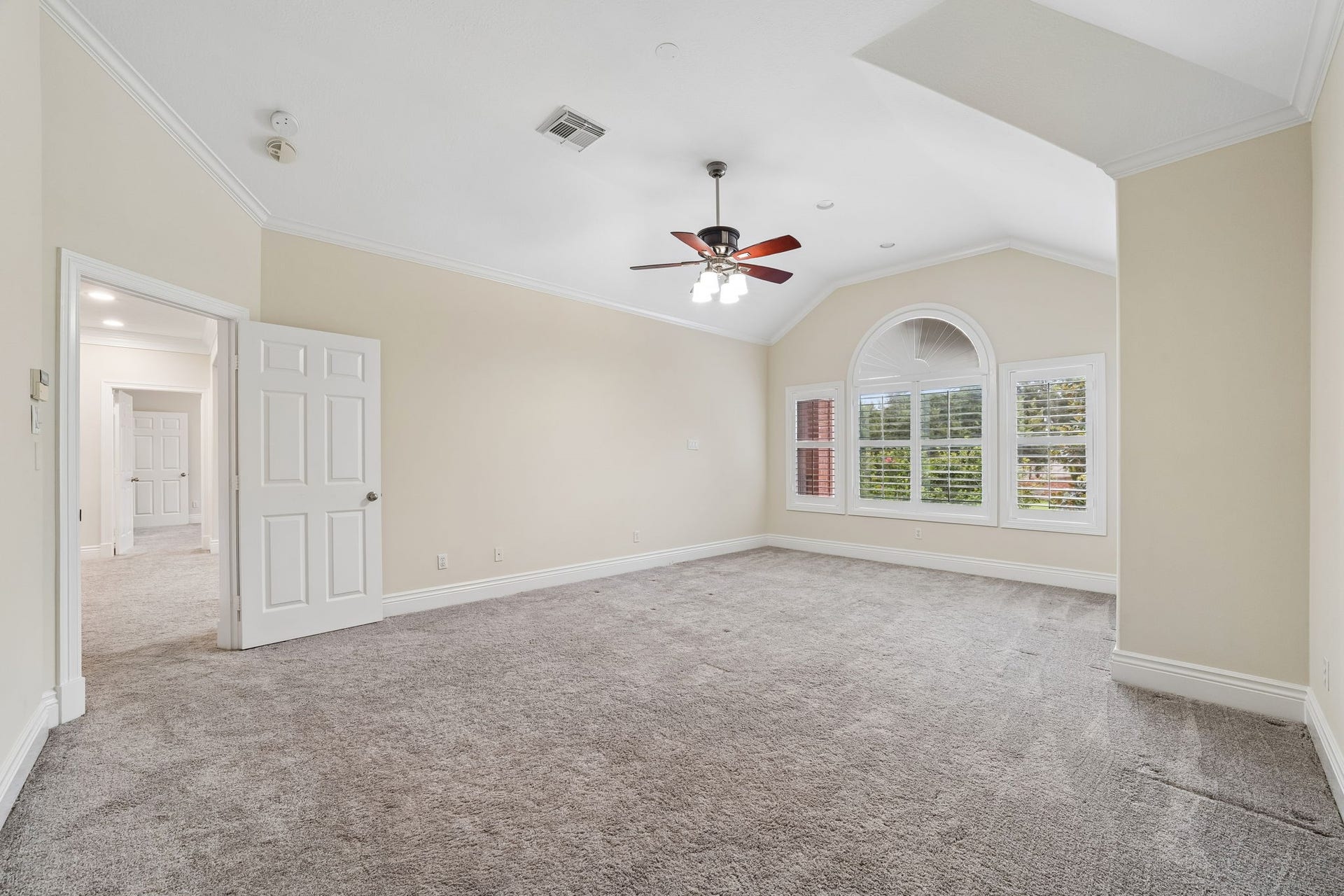 Spacious Master Bedroom with plush carpeting, and large windows featuring elegant shutters for natural light.