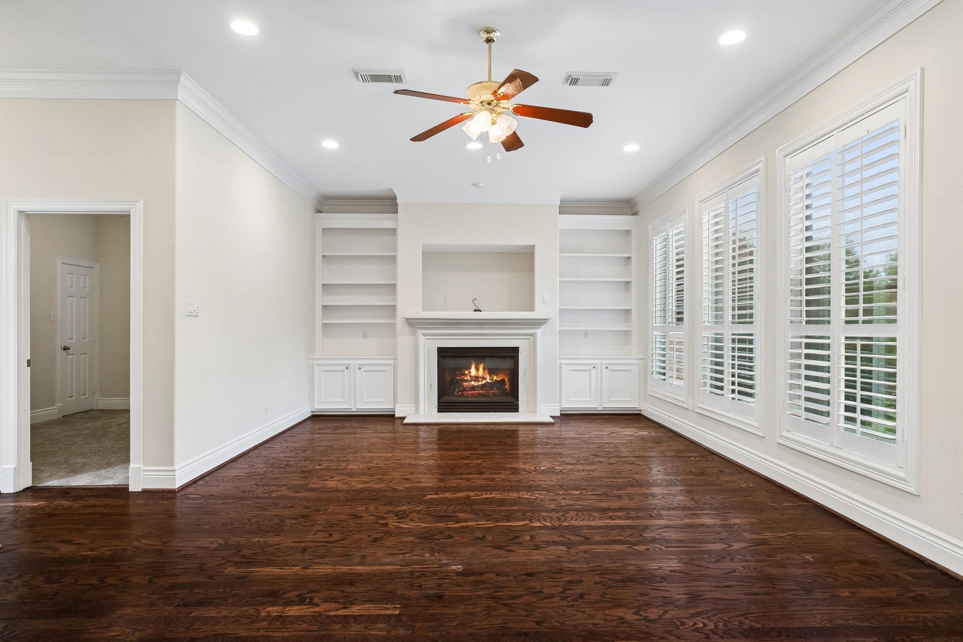 Spacious Family room with rich hardwood floors, a cozy fireplace, and built-in shelving, complemented by abundant natural light.