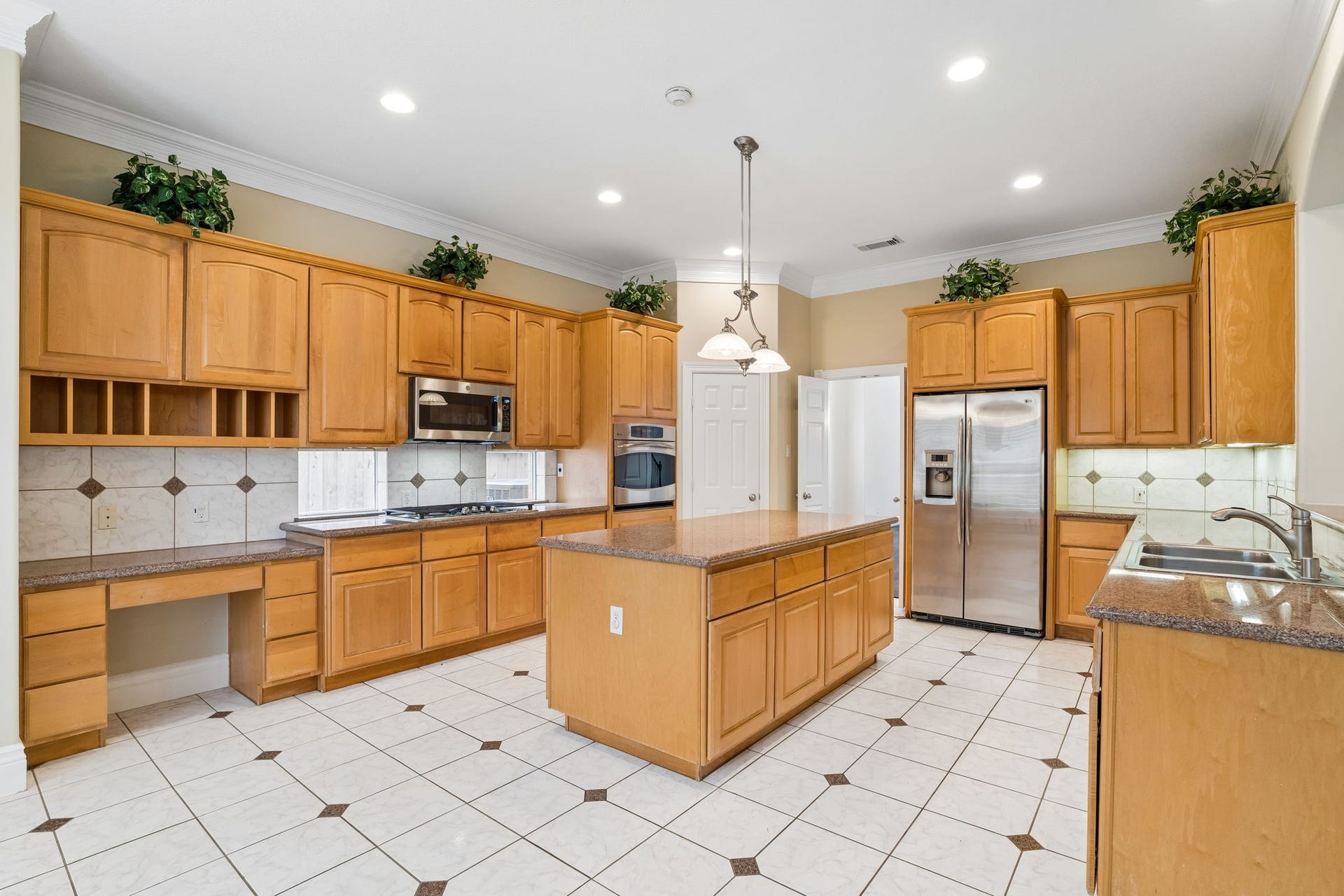 Spacious kitchen with a large central island, stainless steel appliances, and ample natural light from large windows, perfect for culinary enthusiasts and entertaining.