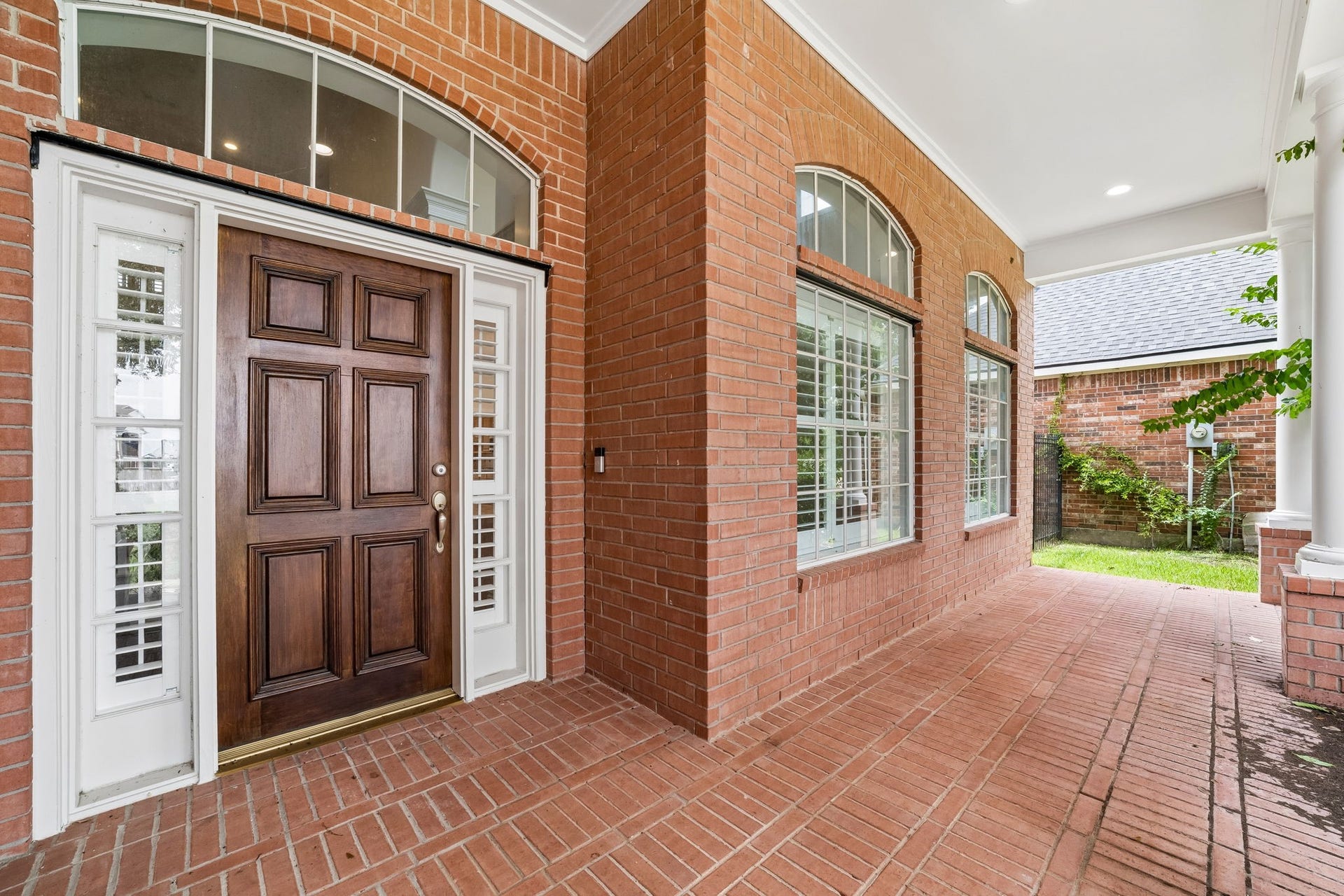 Spacious covered front porch with brick flooring and stylish French doors, perfect to install outdoor furniture for a quiet reading place overlooking the lake in front of the house.