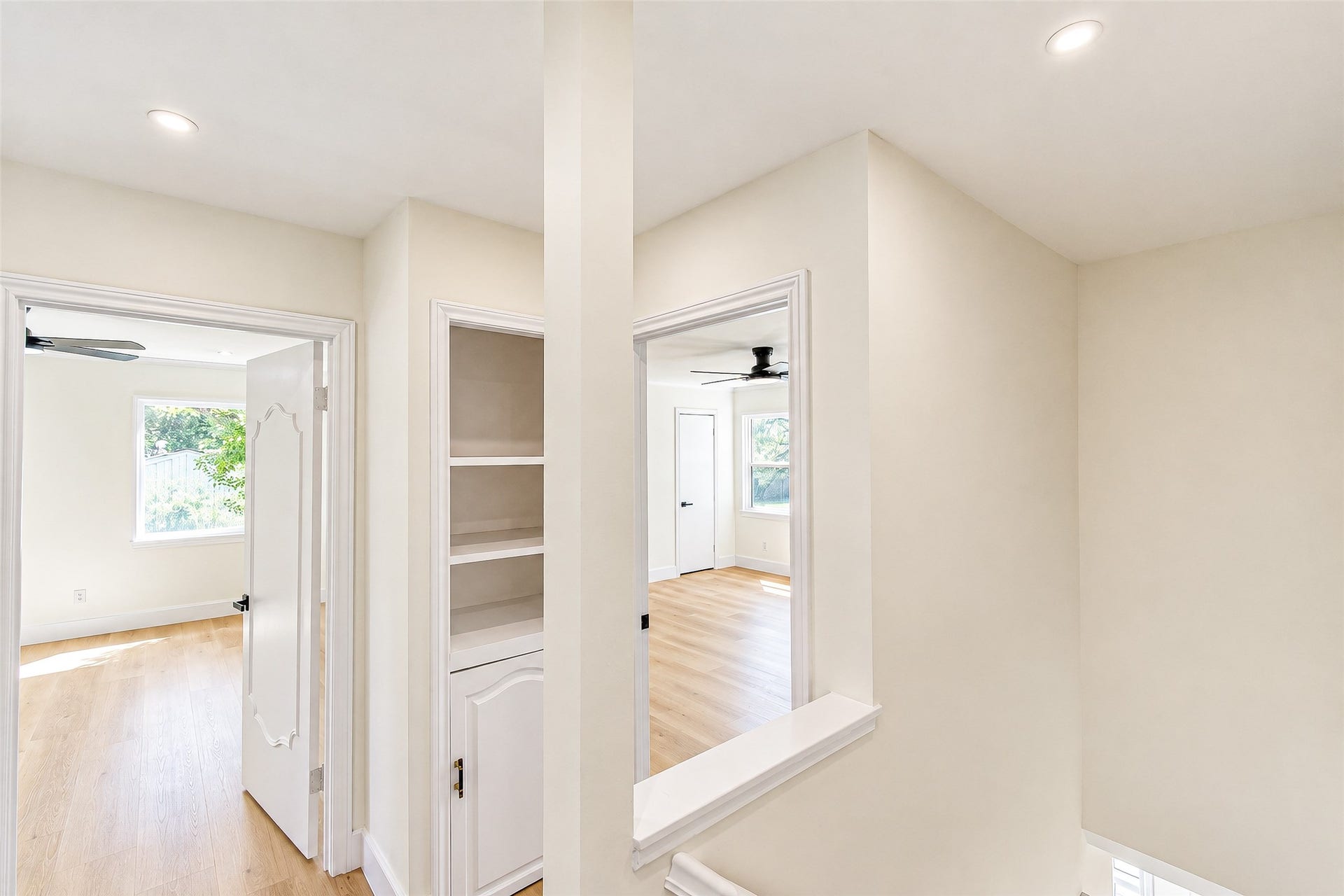 10610 Overbrook Lane, Houston, TX 77042 Bright and airy hallway with built-in shelving and access to spacious rooms featuring large windows and sleek ceiling fans.