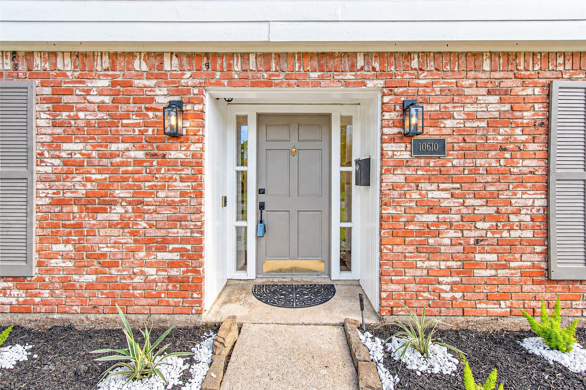 10610 Overbrook Lane, Houston, TX 77042 Charming brick facade with modern gray door and sidelights, framed by tasteful landscaping and elegant lighting, creates a welcoming entryway.